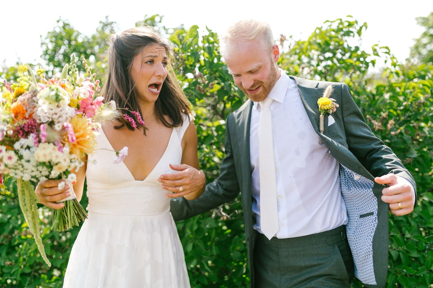 Wedding celebration in garden with couple dancing and guests enjoying champagne among blooming flowers.