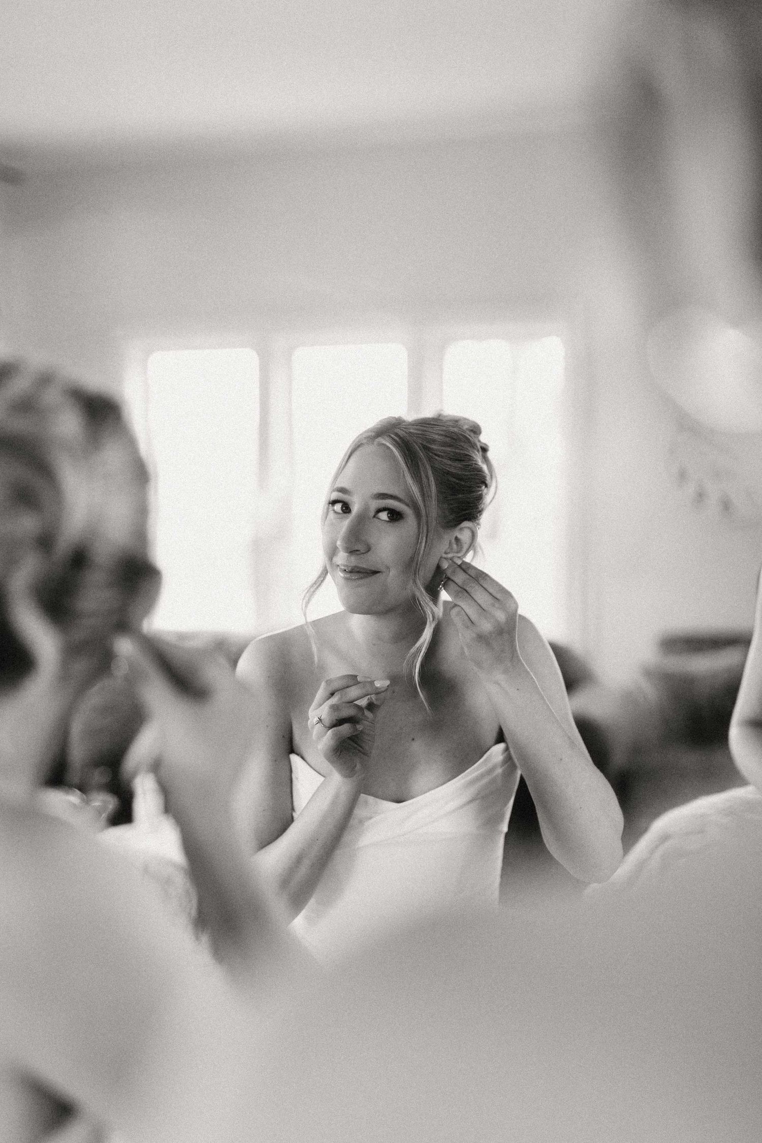 A series of black and white images showing someone getting ready and applying makeup in a bright interior space.