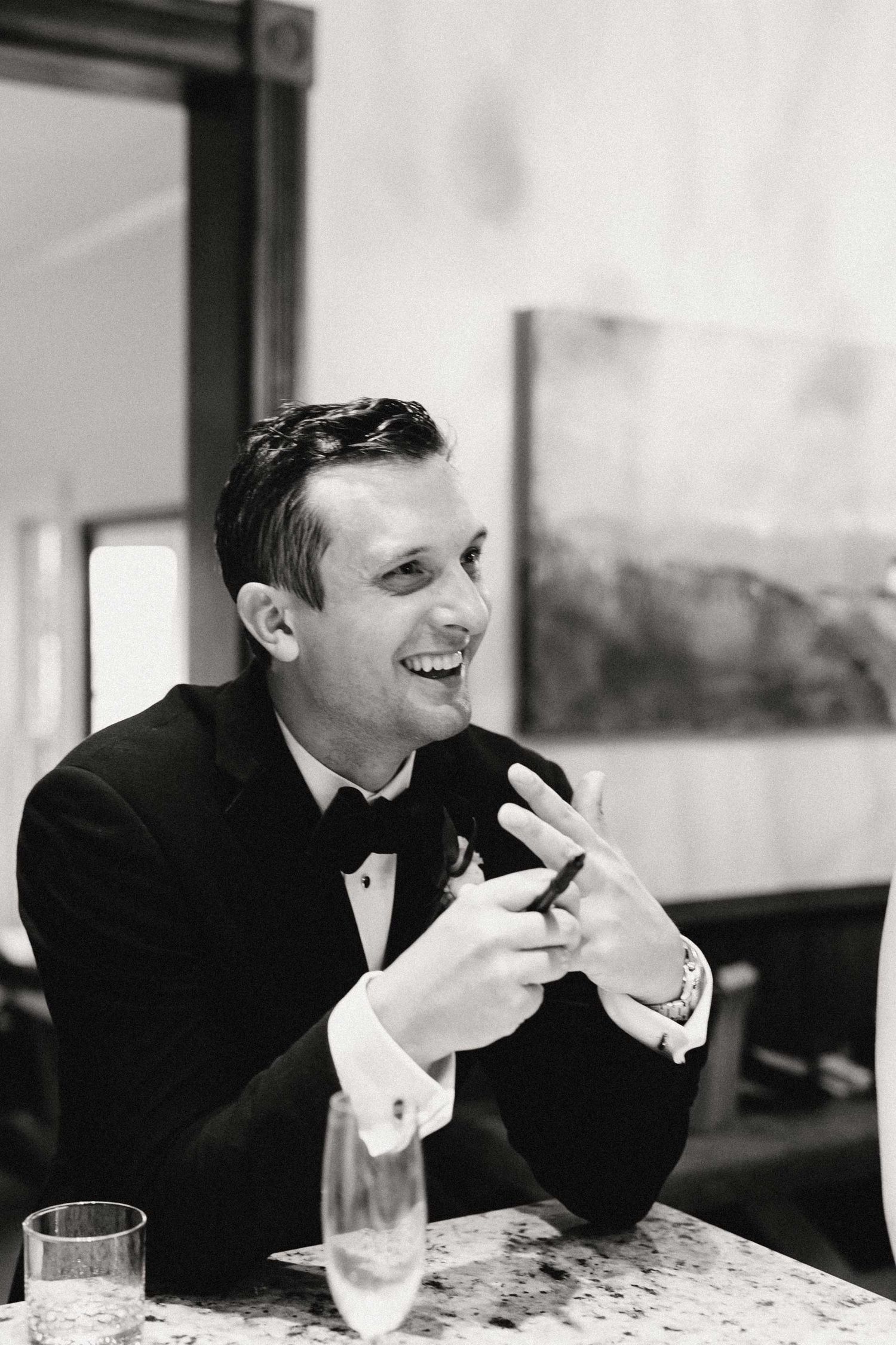 A series of black and white photos showing someone seated at a table gesturing and laughing.