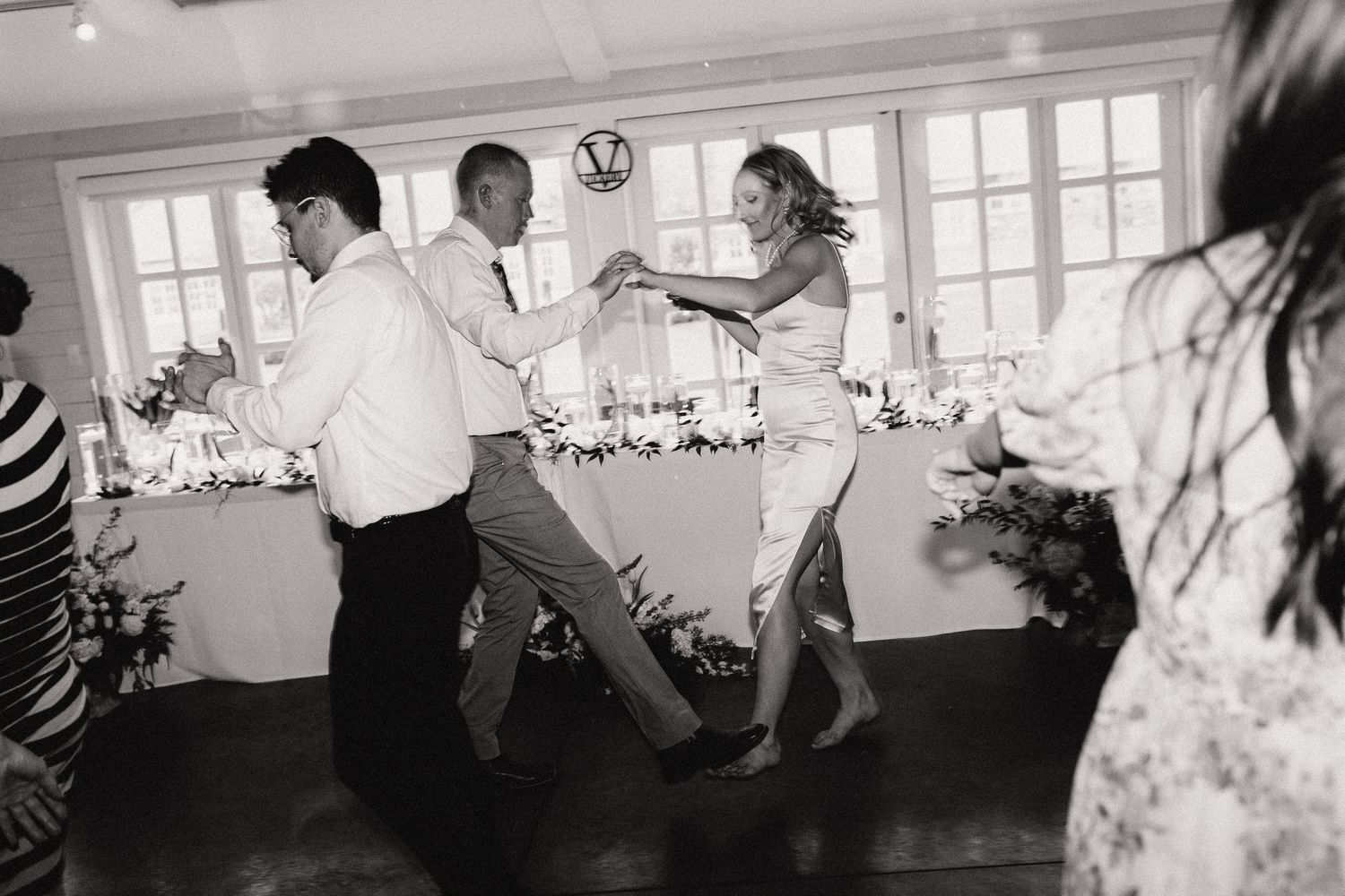 People celebrate and dance in a black and white sequence showing a crowded dance floor at what appears to be a party.