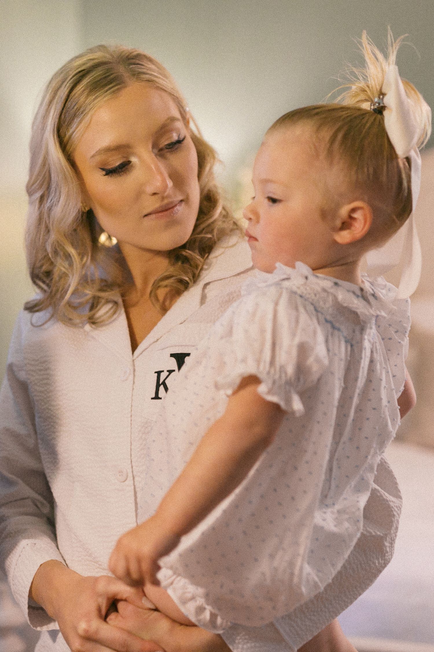 A tender moment captured in soft lighting with a baby wearing a light colored ruffled outfit.