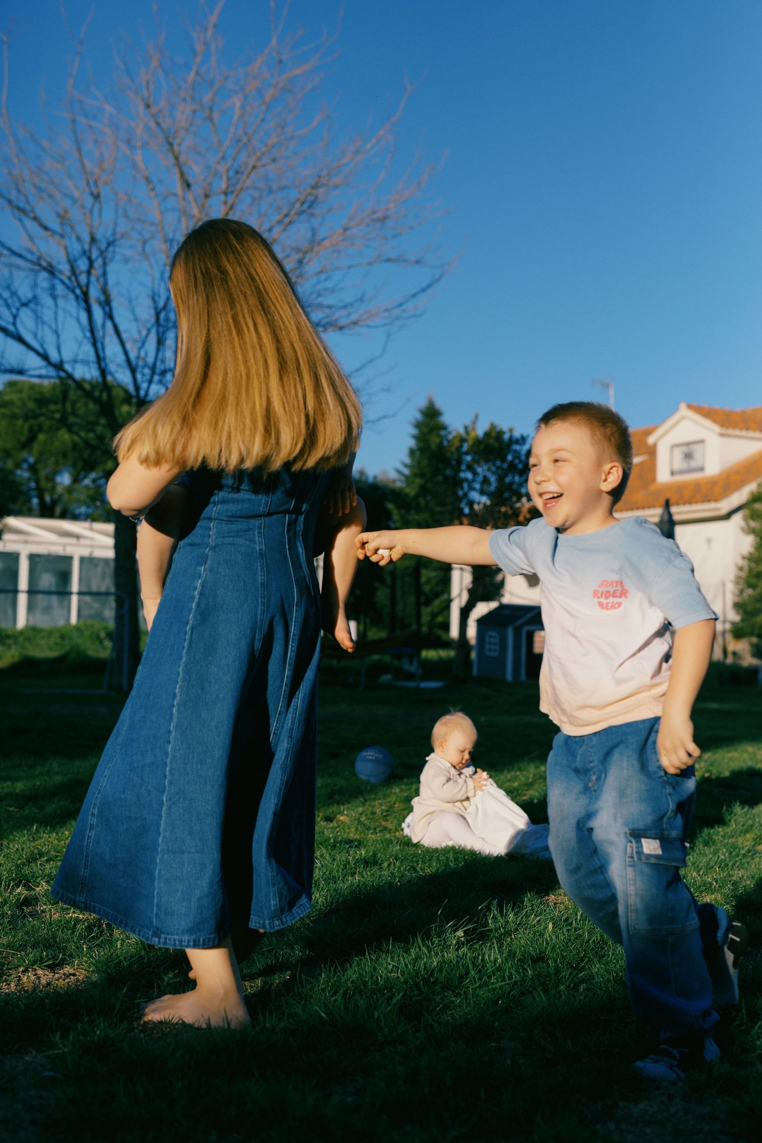Happy boy laughing while playing with a girl in a sunny backyard garden.