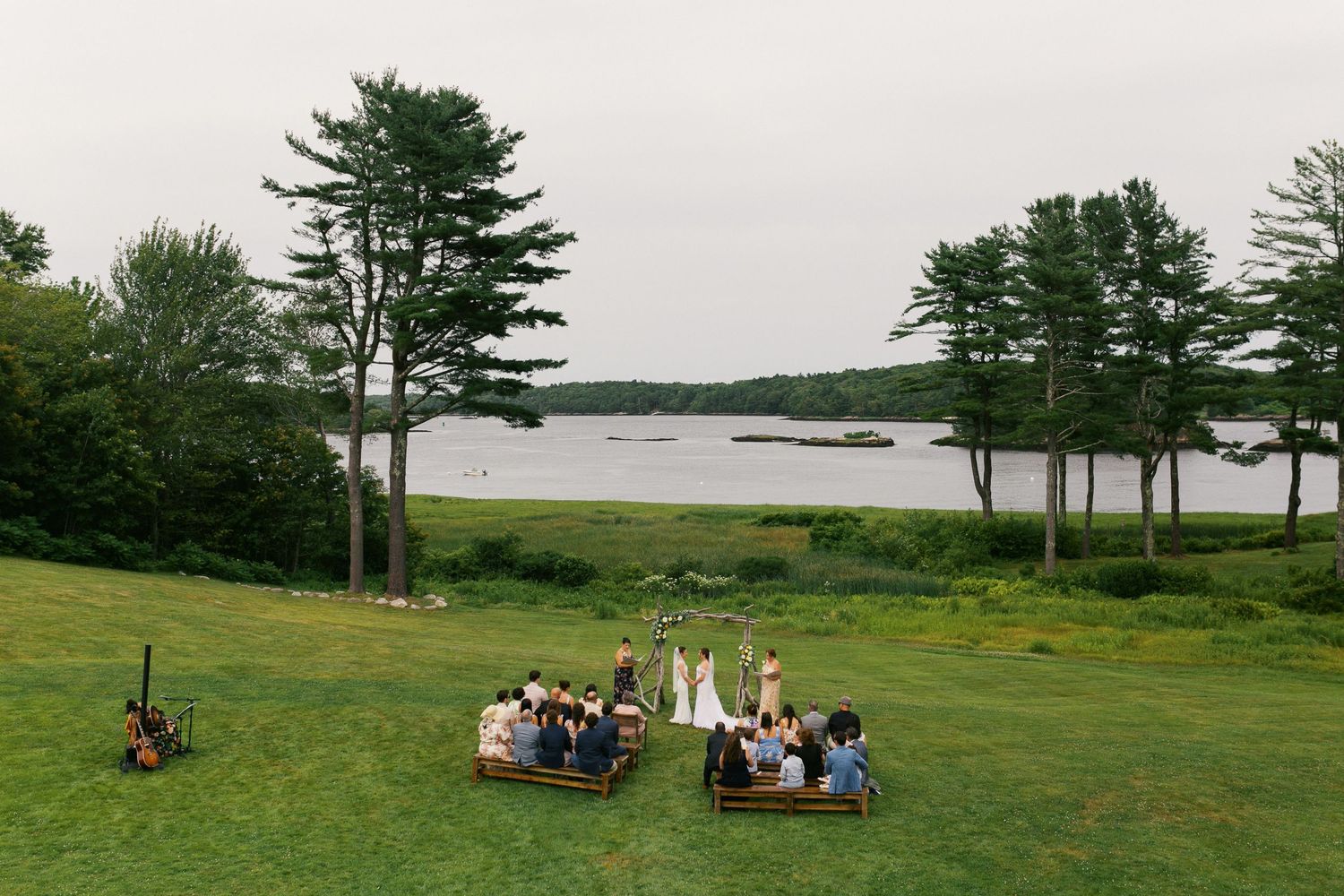 Scenic coastal Maine landscape with evergreen trees and grassy fields where two brides marry at the 1774 Inn on a summer day.