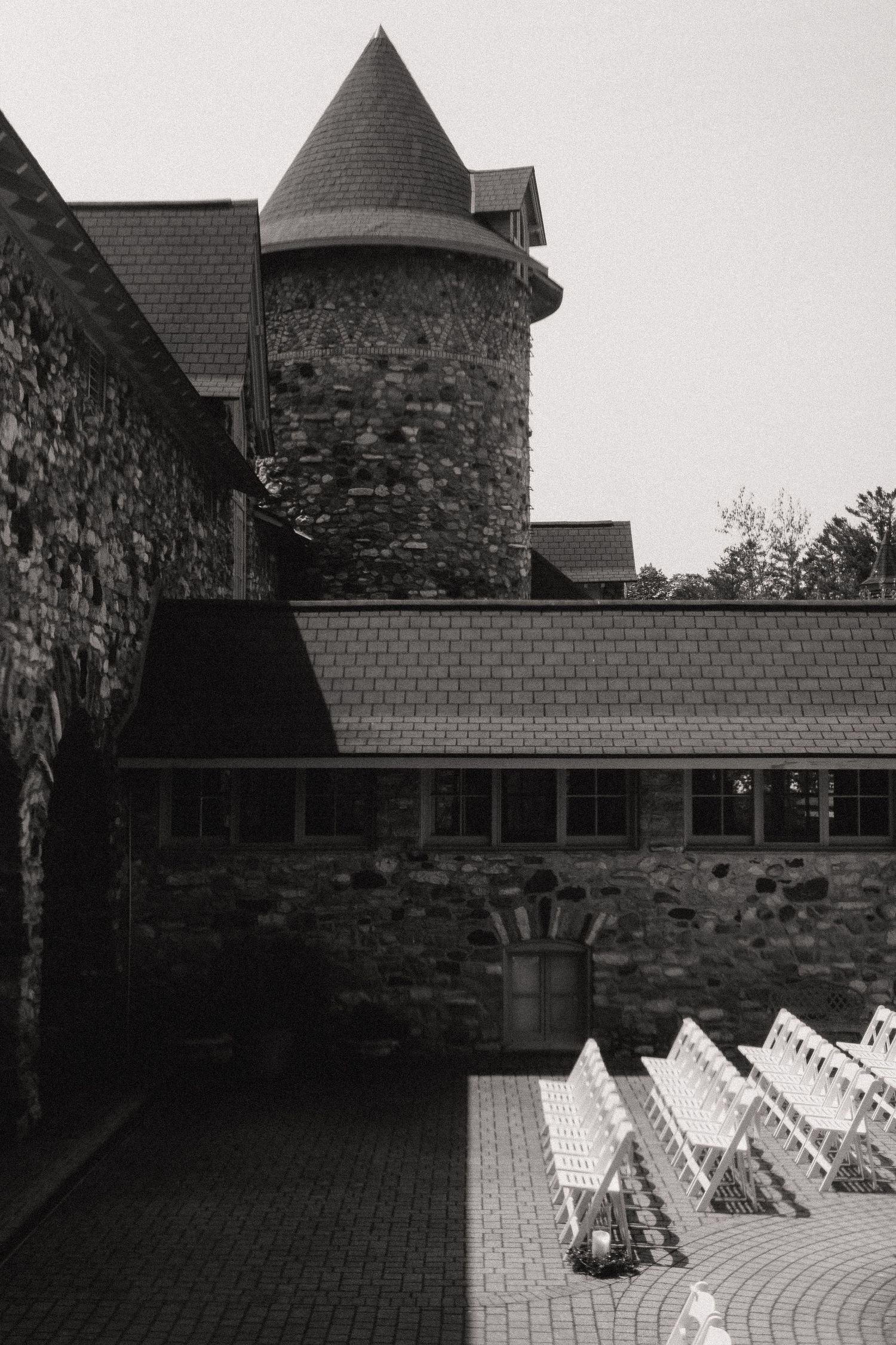 Black and white architectural shot of stone building with outdoor seating arrangement.