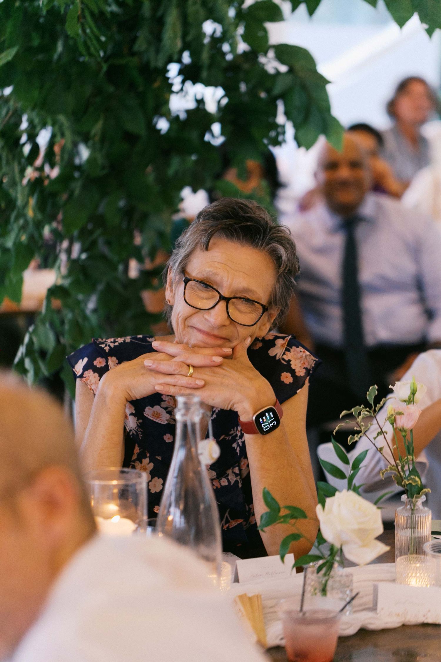 A series of candid dinner party photos showing guests seated at a table with wine glasses and green foliage overhead.