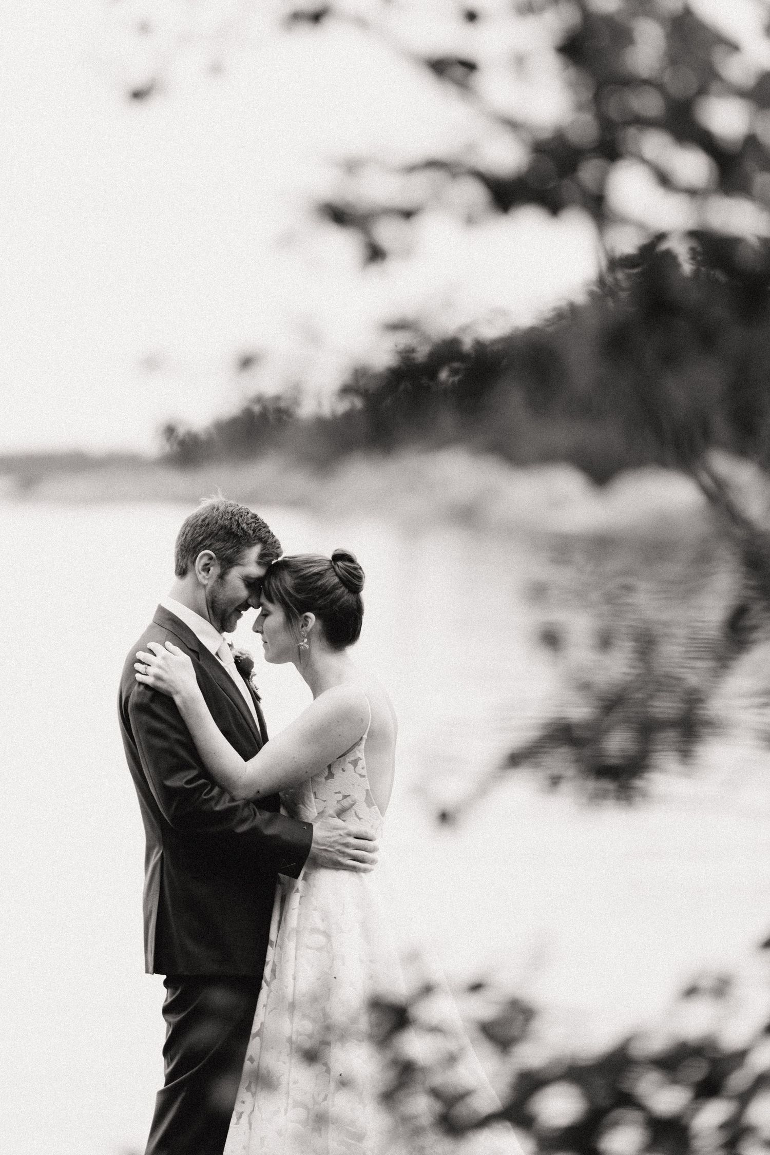 A romantic black and white photo of a couple embracing outdoors with a dreamy bokeh background.