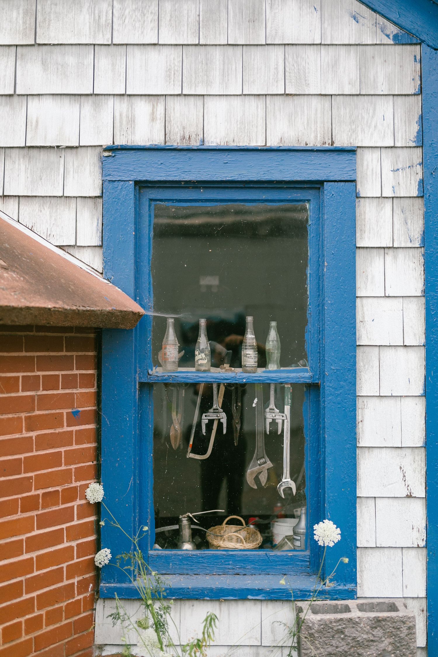 White building with blue trim features vintage shoes displayed in window sills.