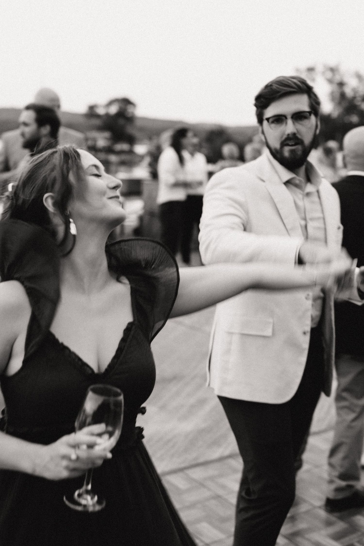 Black and white photos of wedding guests dancing and celebrating at an outdoor reception.