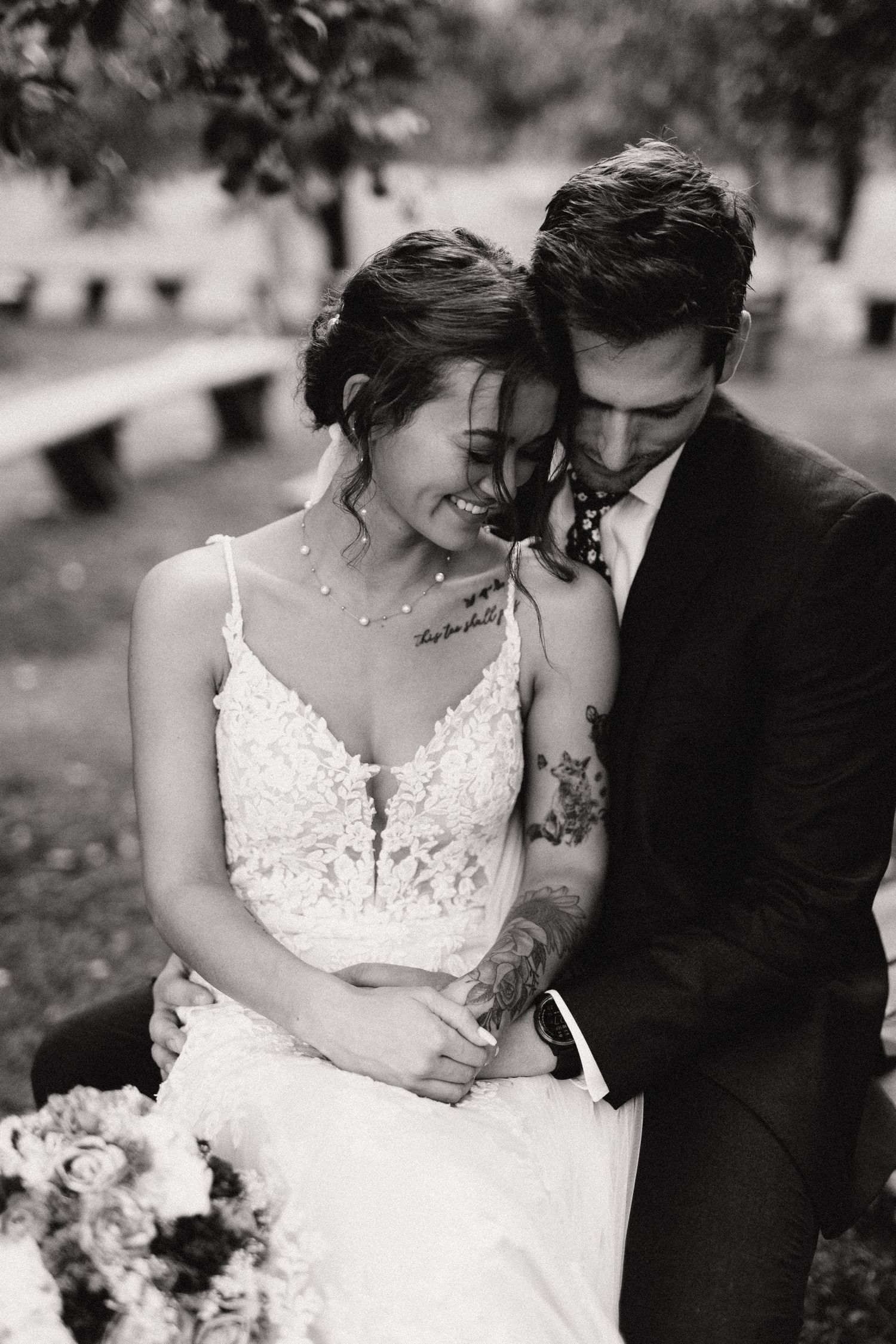A tender black and white wedding portrait shows a couple sharing an intimate moment together in a garden setting.