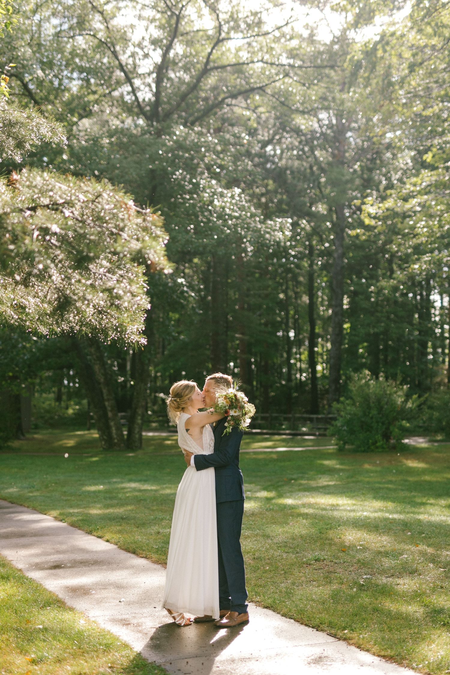 A romantic outdoor wedding moment under blooming trees with sunlight filtering through the branches.