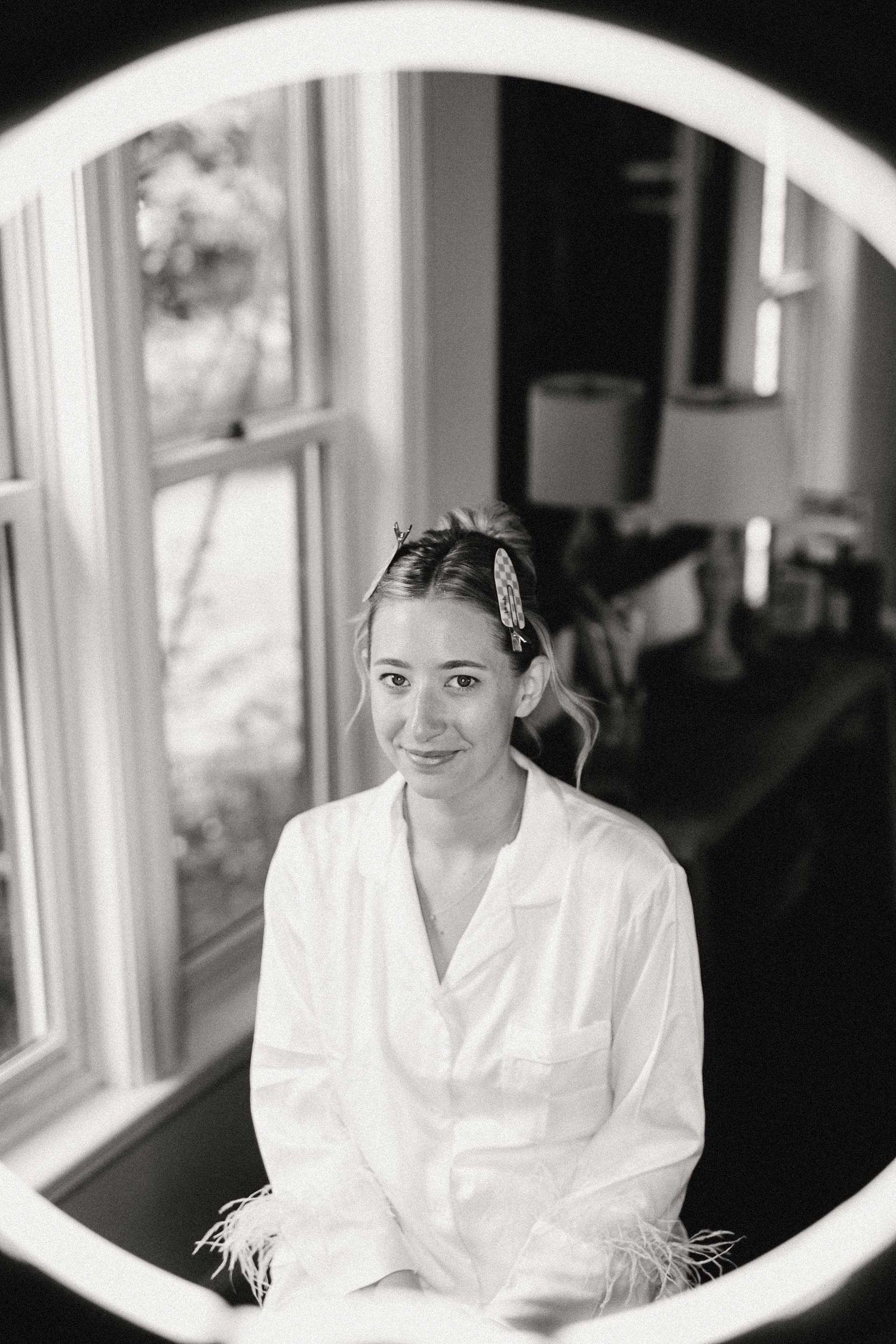 A black and white photo series showing someone in a white robe sitting by windows in different poses.