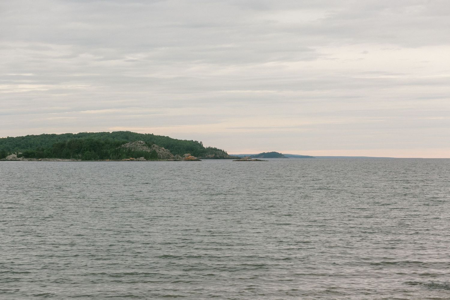Panoramic view of a tranquil ocean coastline with rocky islands and calm waters stretching to the horizon.