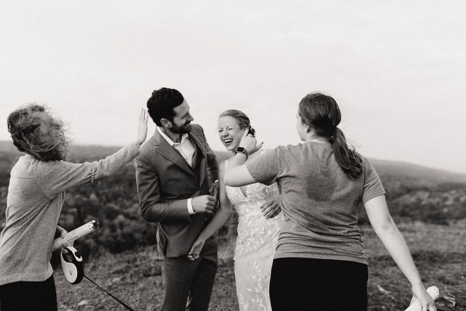 A celebratory moment captured in black and white on a mountaintop with guests gathered together.