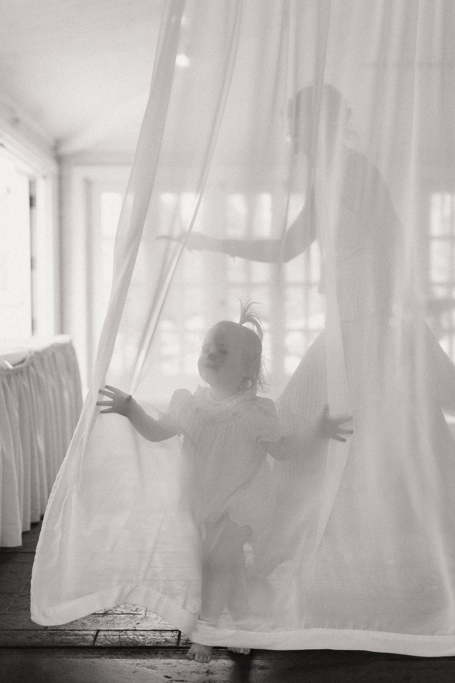 Black and white series showing silhouettes playing behind translucent white curtains creating dreamy shadows.