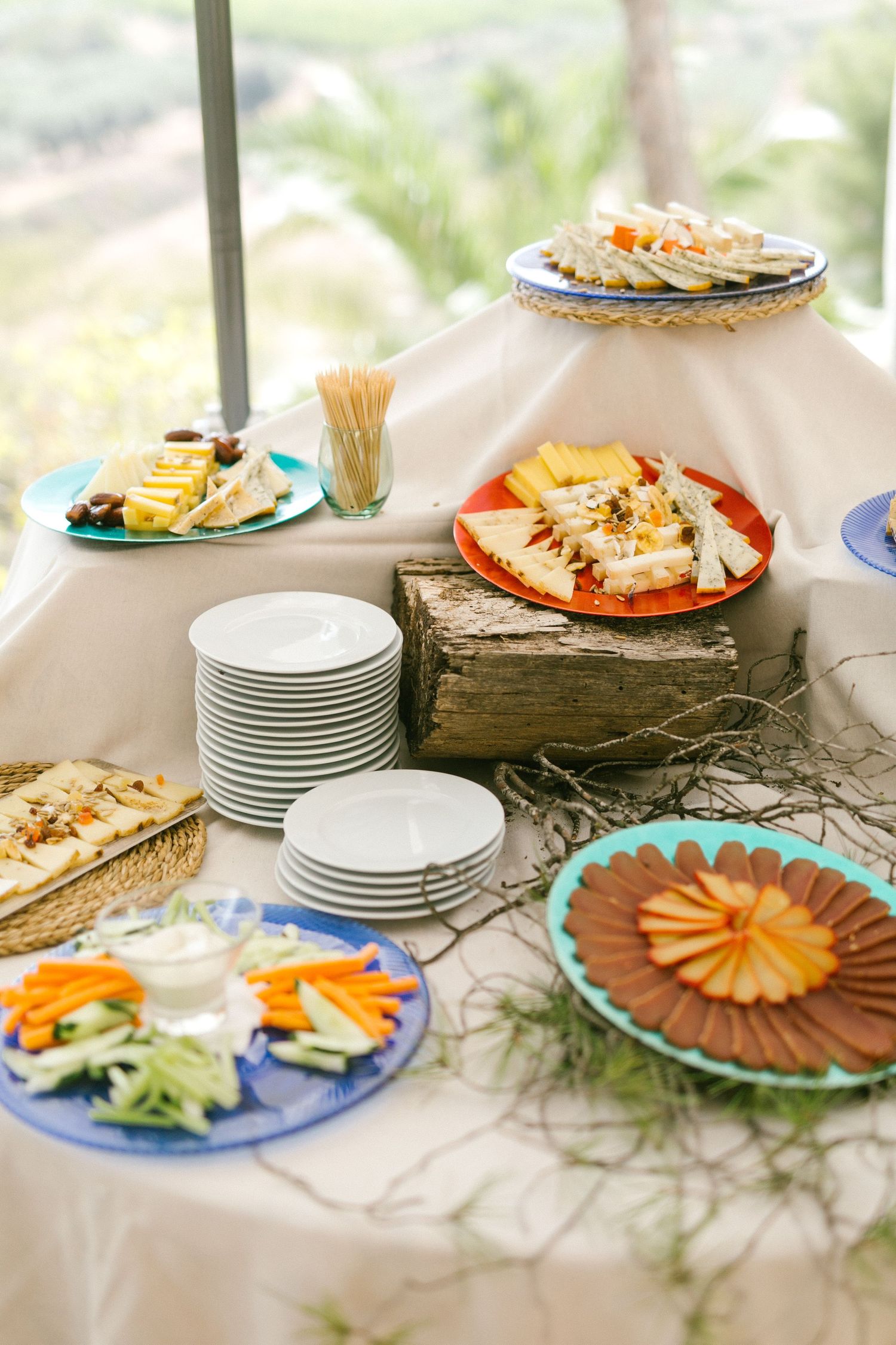 Appetizer and hors d'oeuvres buffet table with assorted plates of meats, cheeses, and vegetables on white tablecloth.
