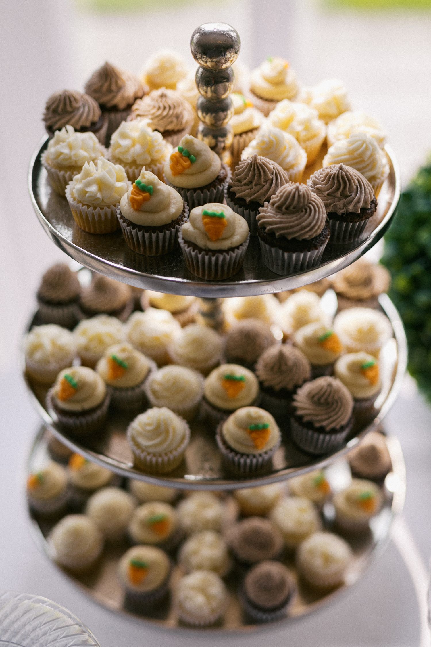 A tiered display of mini cupcakes with chocolate and vanilla frosting decorations.