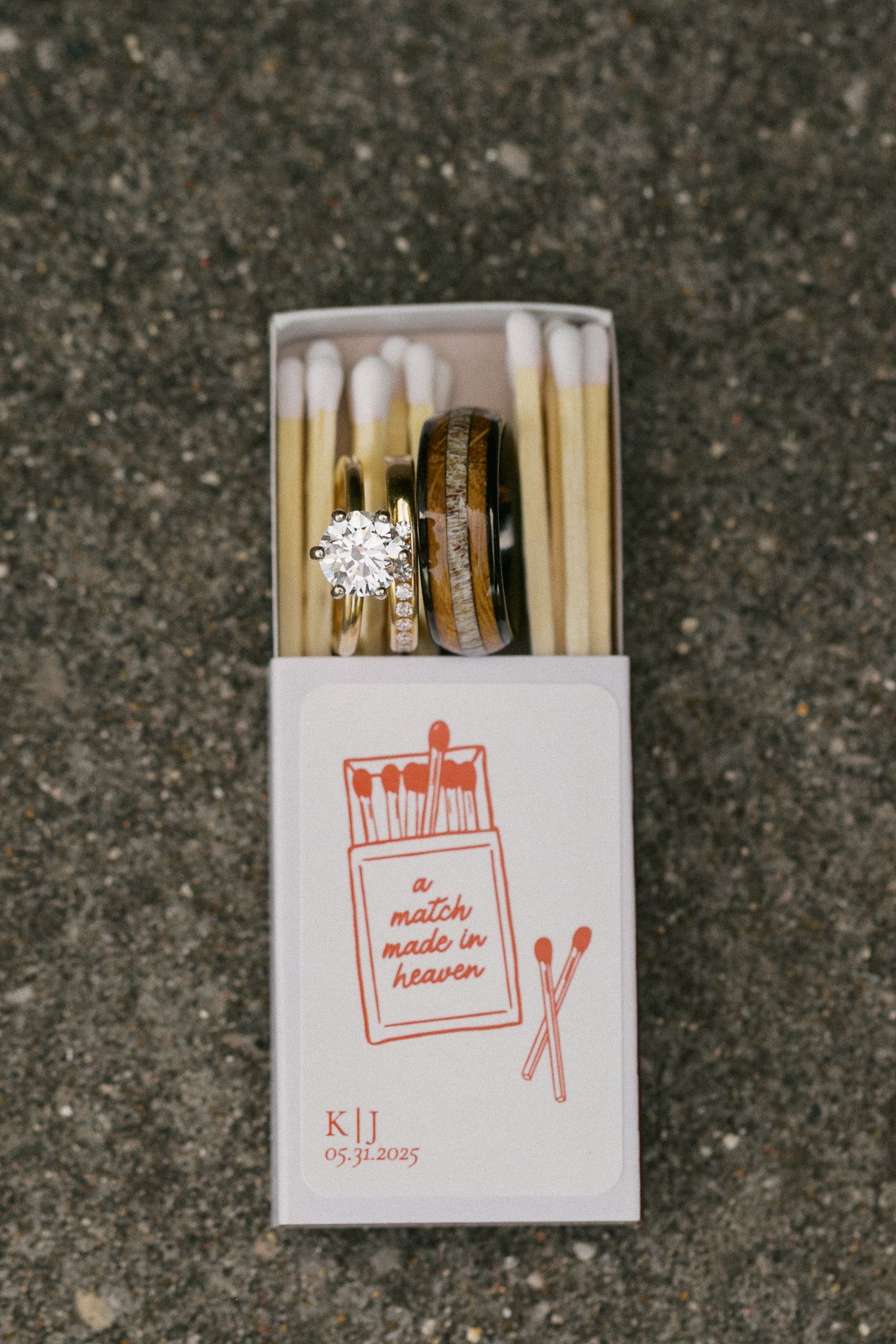 Wedding favor matchboxes with custom designs and decorative details on concrete surface.