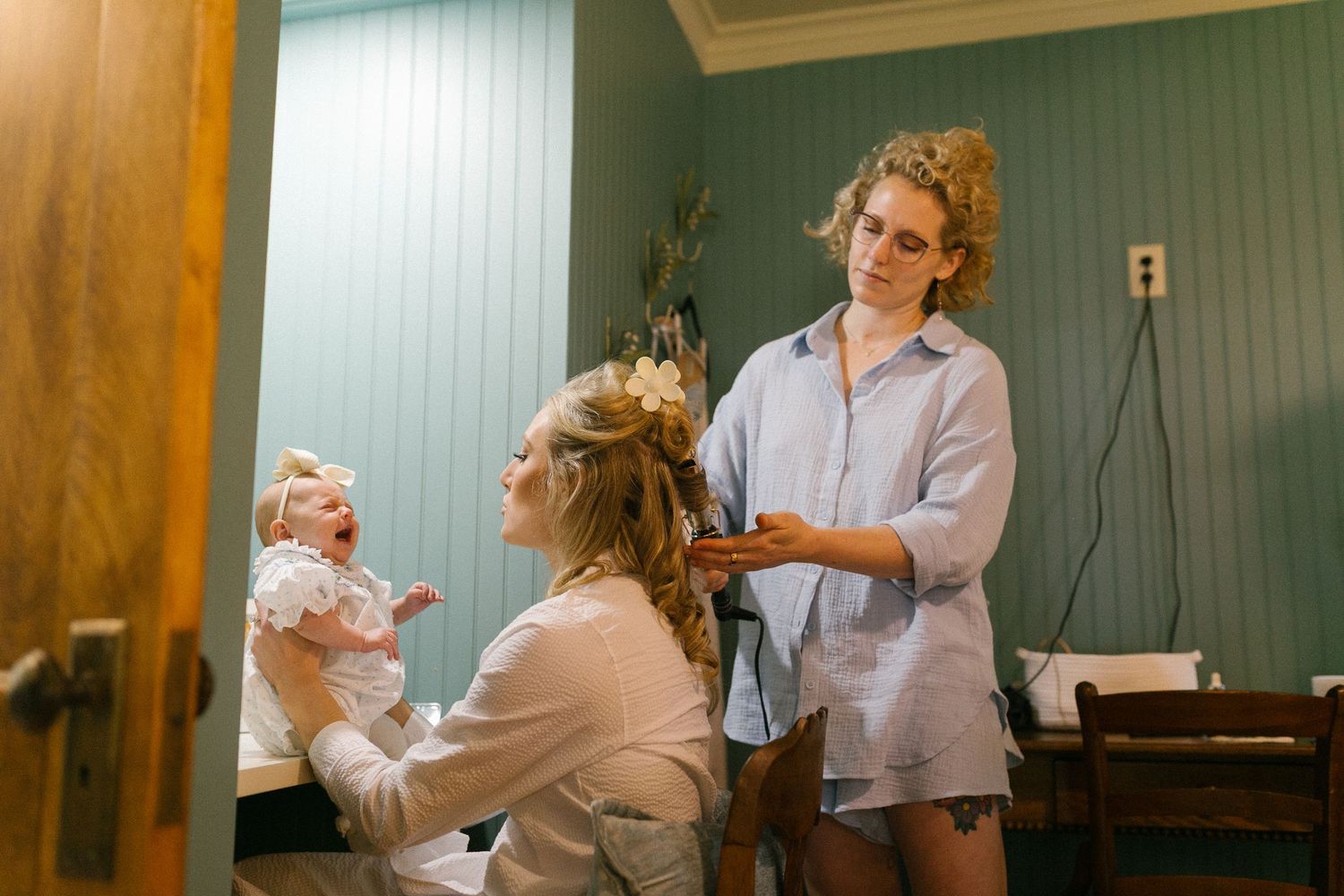 Wedding morning preparation scene in a blue-walled room with soft natural lighting.