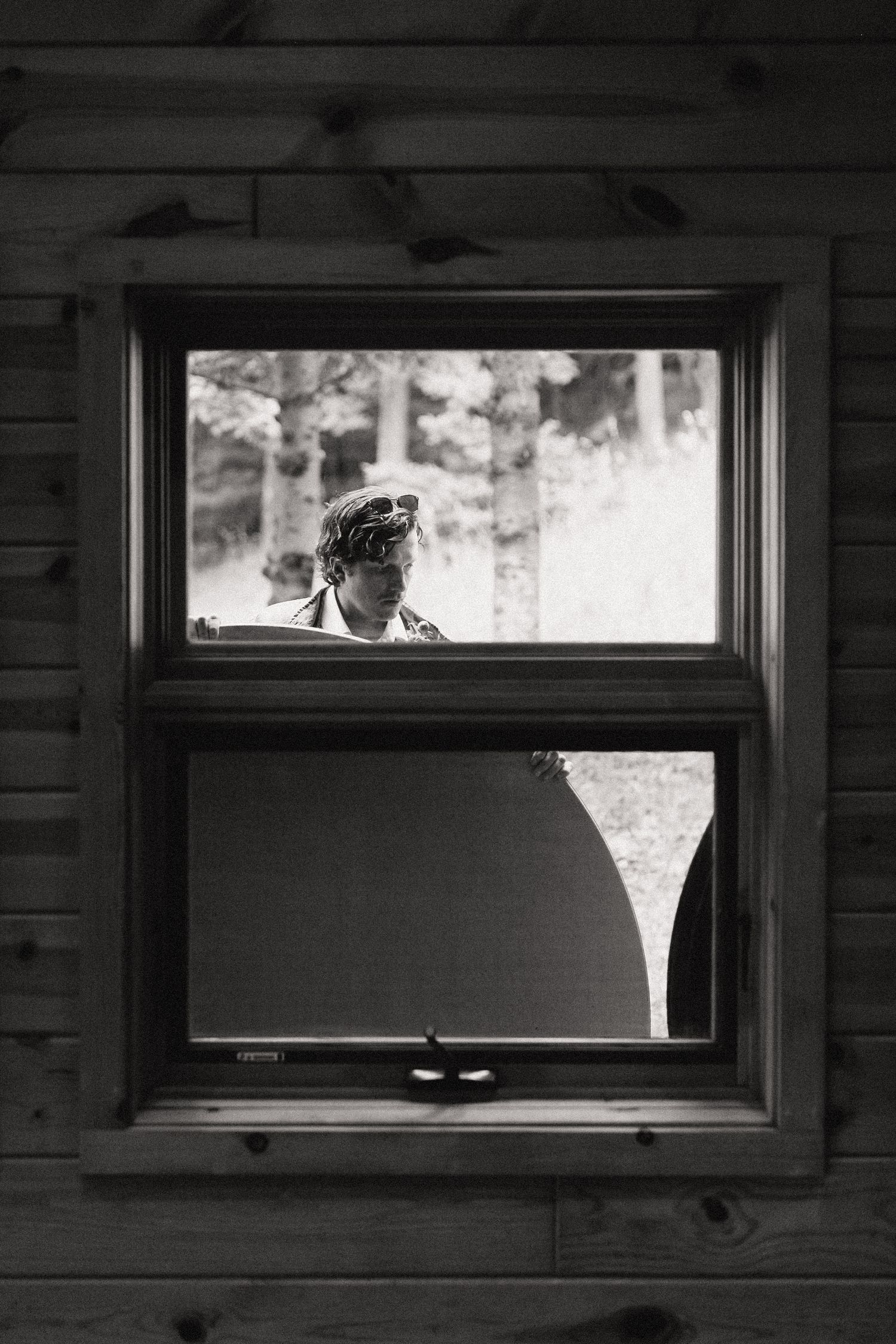 Black and white view through a wooden window frame dividing the scene into two sections with shadows and light.