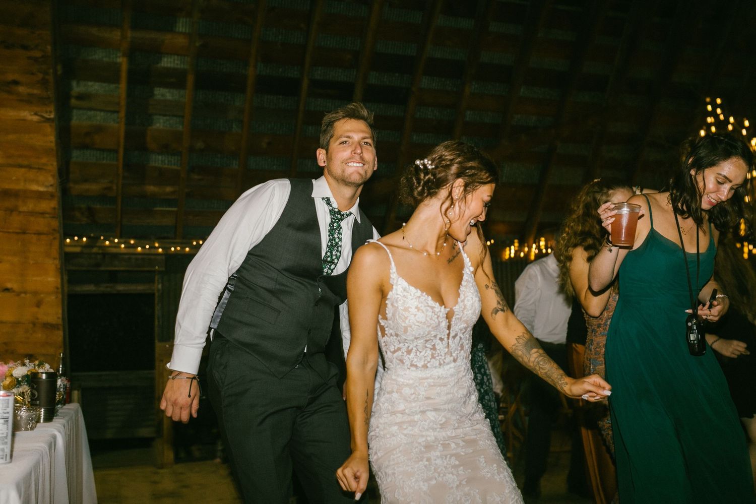Newlyweds celebrate on the dance floor at a rustic barn wedding reception with twinkle lights in the background.