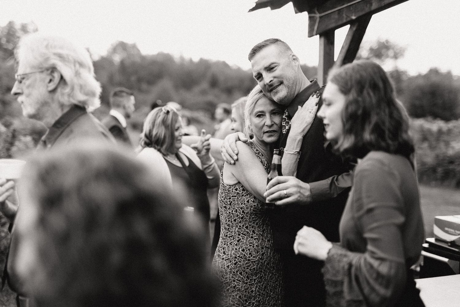 A black and white vintage photograph showing a small group of people gathered together outdoors laughing and socializing.