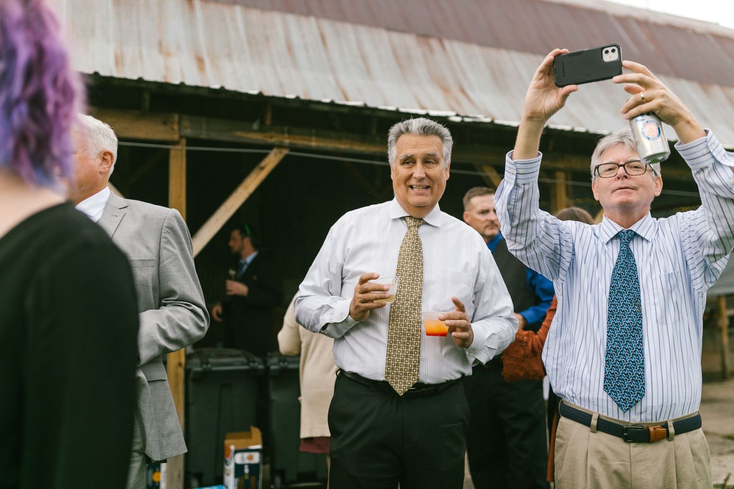 Guests with phones taking photos during outdoor daytime wedding reception.
