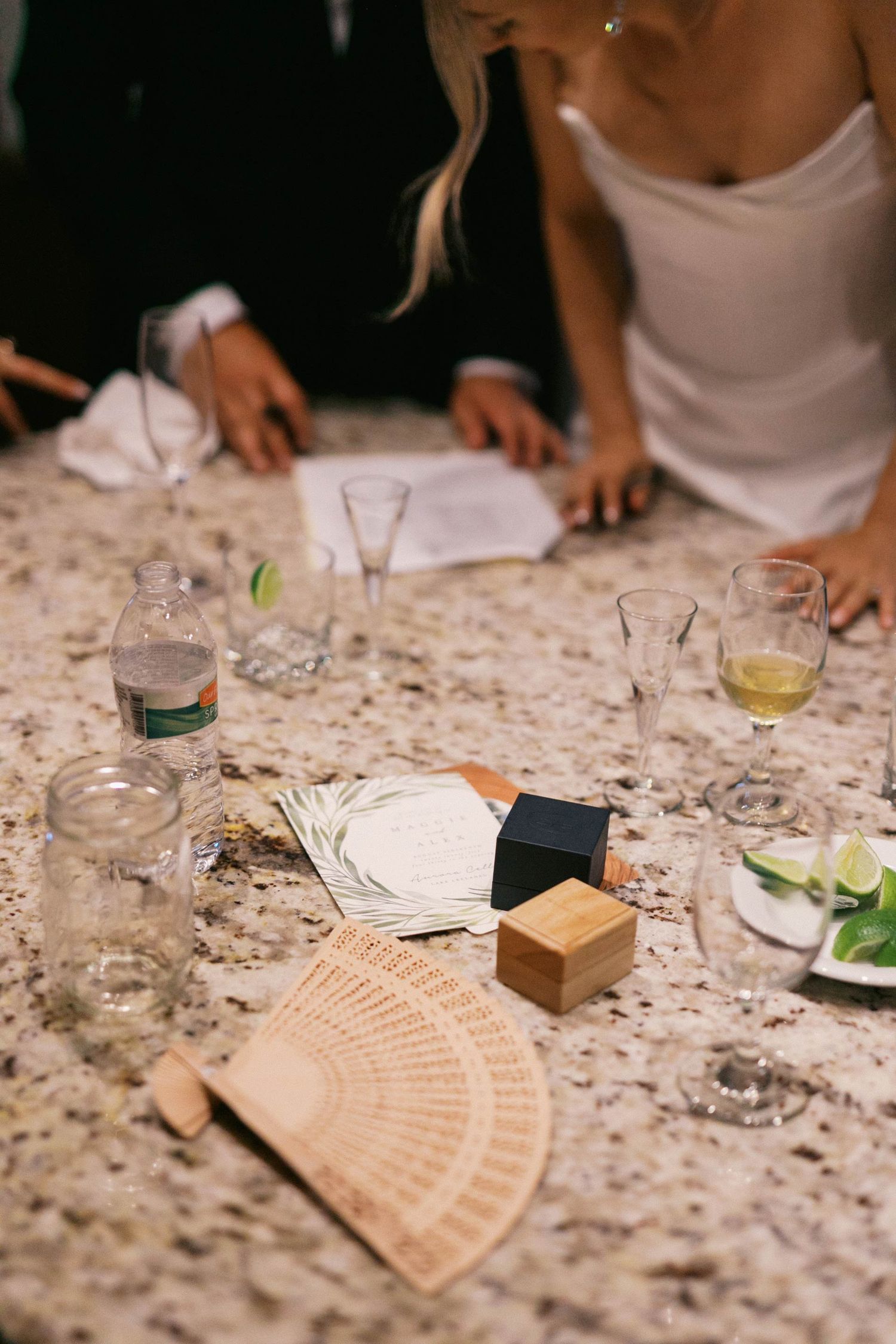 Hands working on a granite countertop with recipe cards and ingredients laid out for cooking preparation.