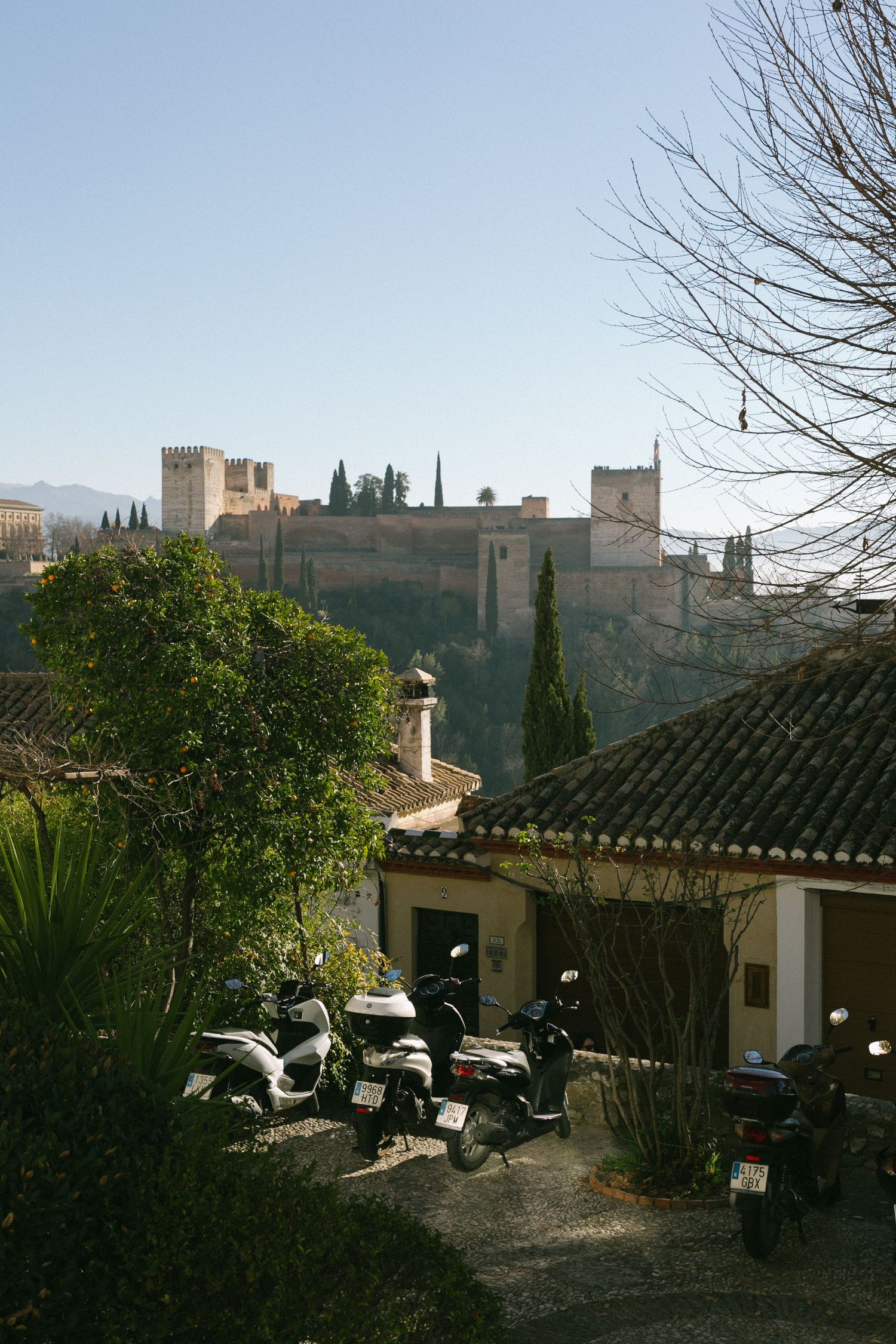 View of the Alhambra palace complex in Granada perched on hillside with parked scooters in foreground.
