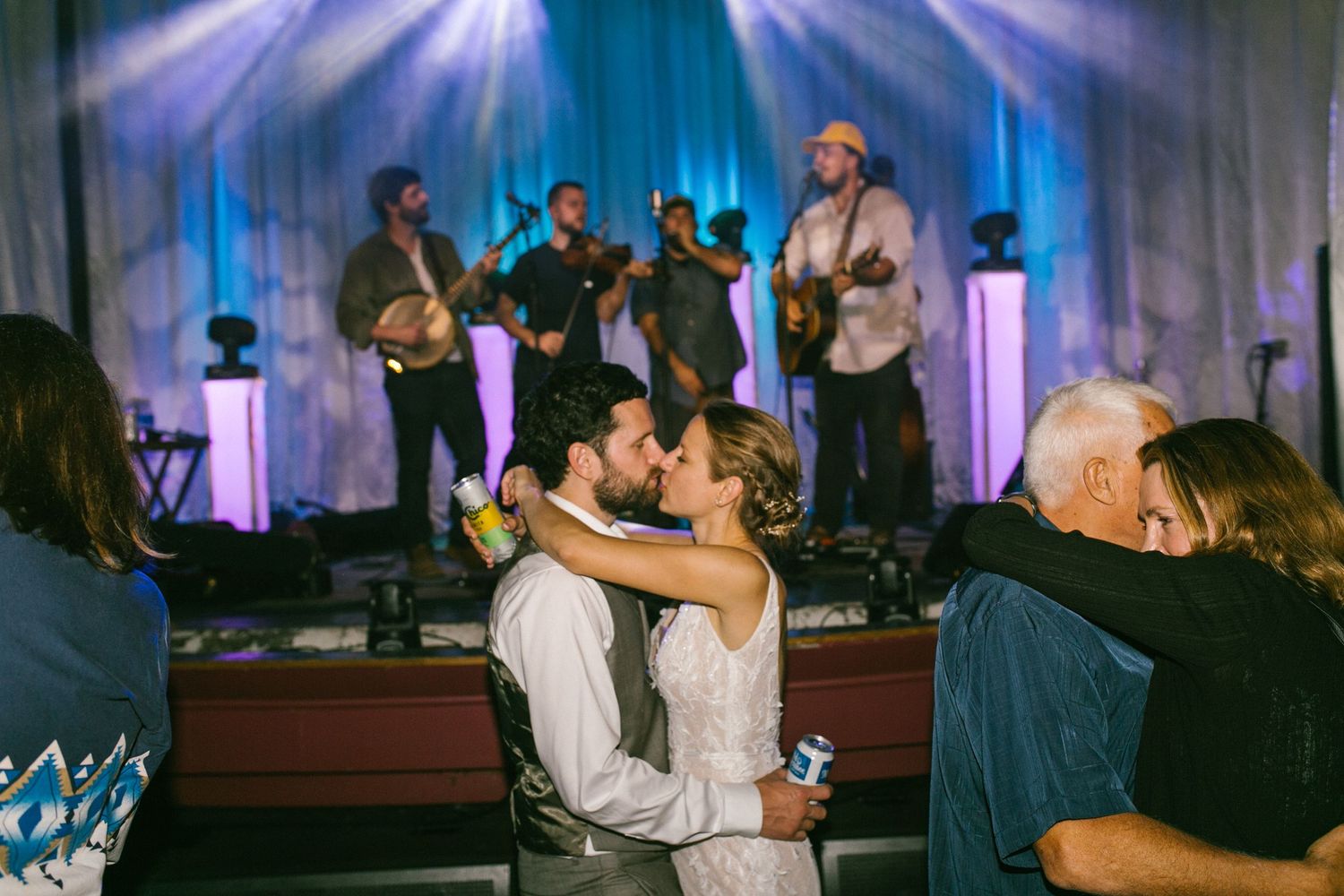 Couples dancing together at a wedding reception with a live band performing on stage.