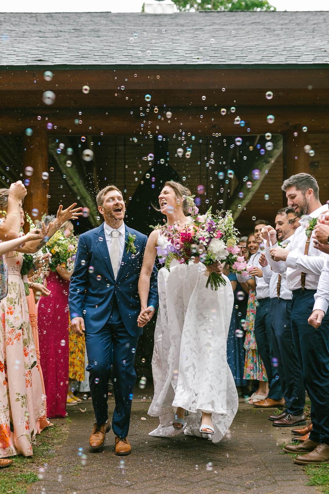 Wedding celebration with guests blowing bubbles during an outdoor reception.