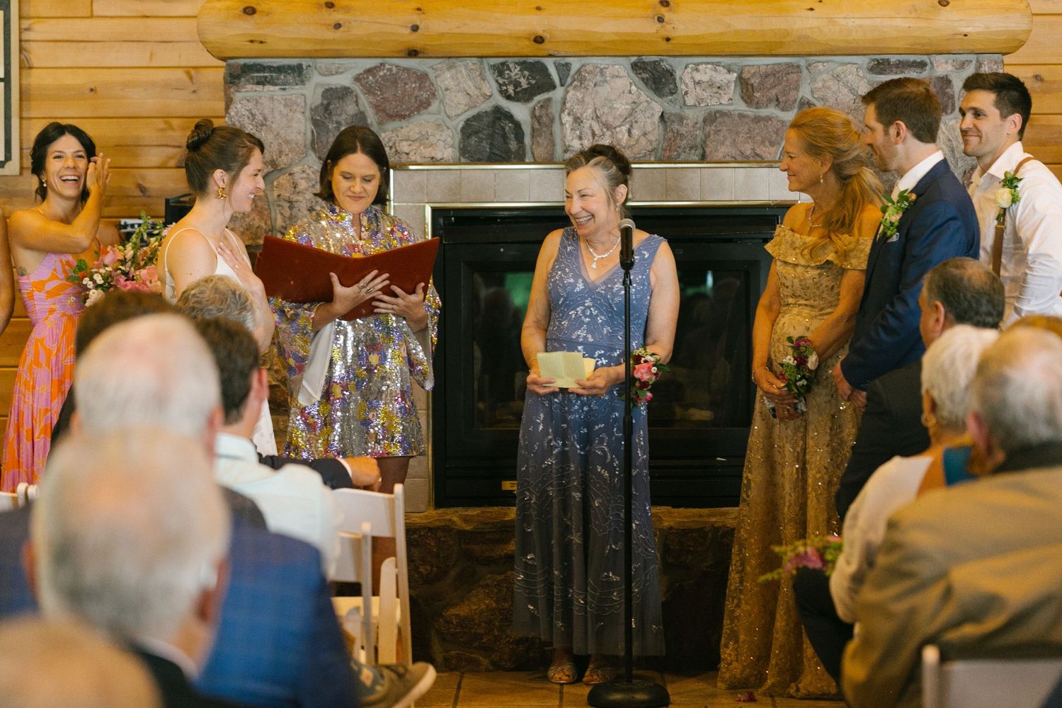 Wedding ceremony taking place in a rustic lodge venue with stone fireplace and wooden beams.