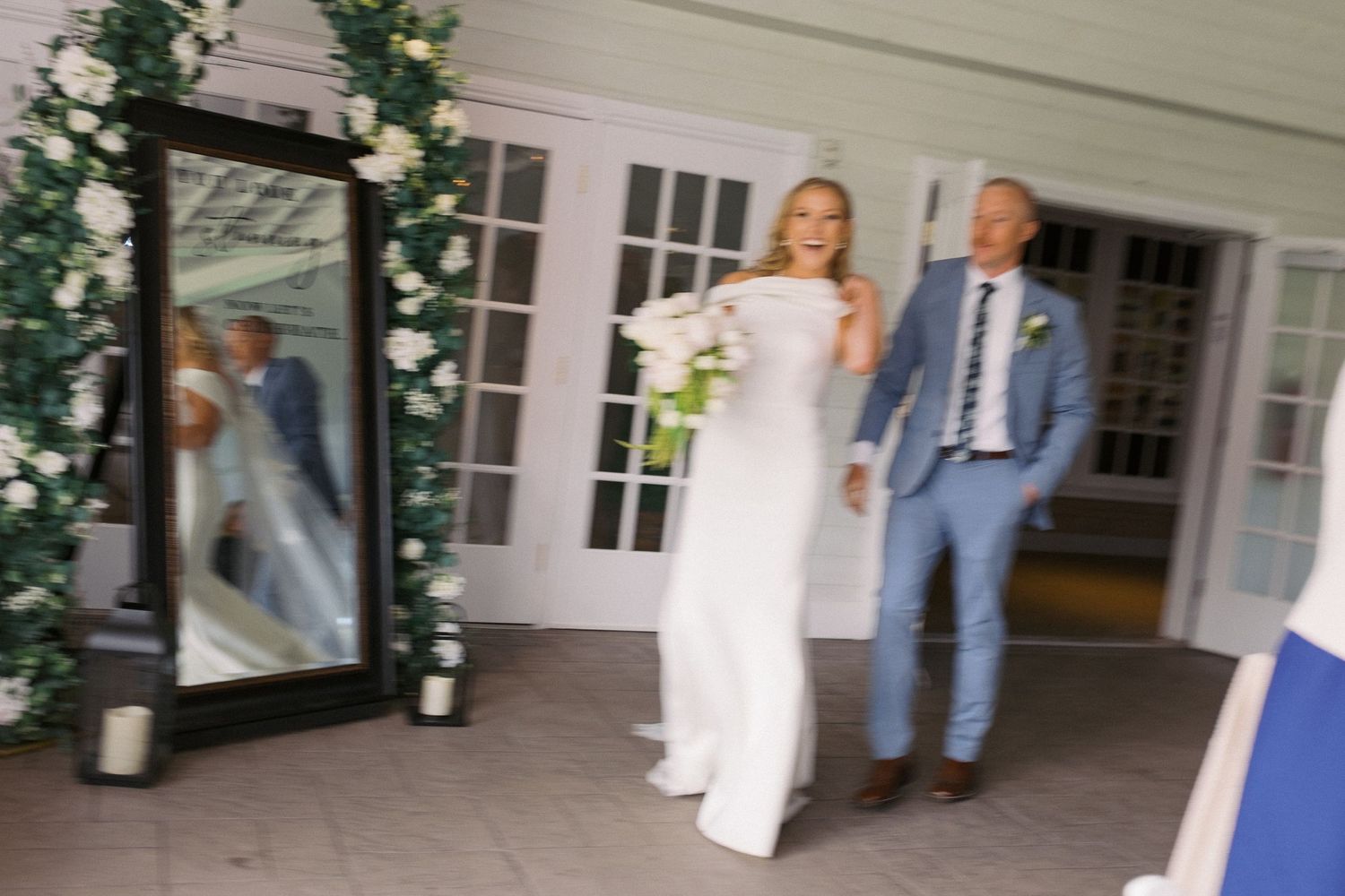 A wedding couple shares a romantic dance under a covered outdoor patio area with white columns.