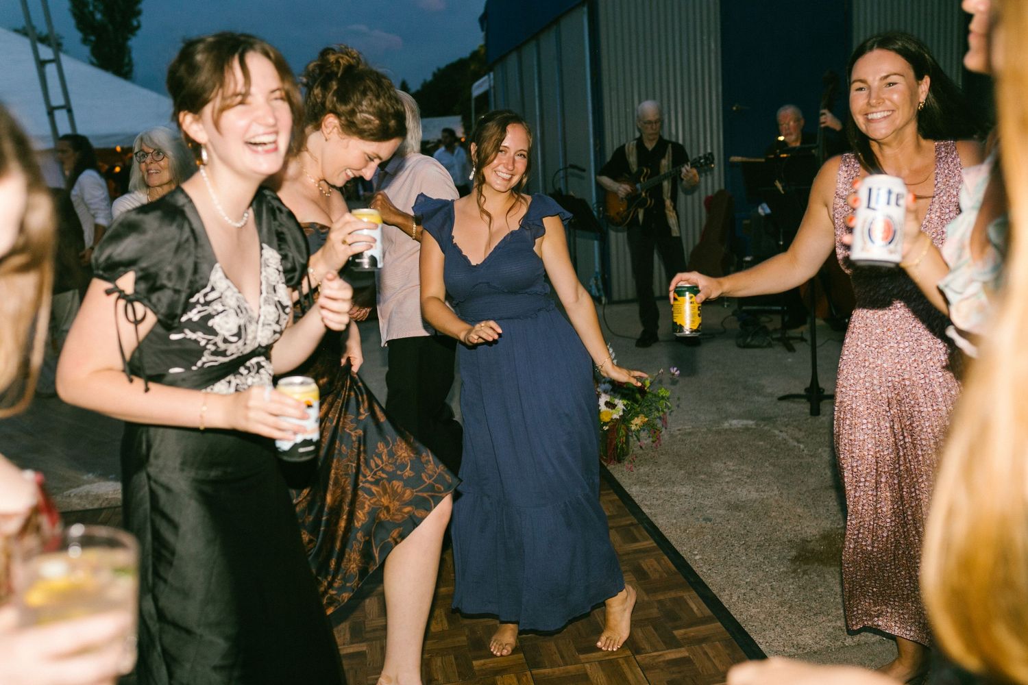 Wedding guests dancing and celebrating at an evening reception party.