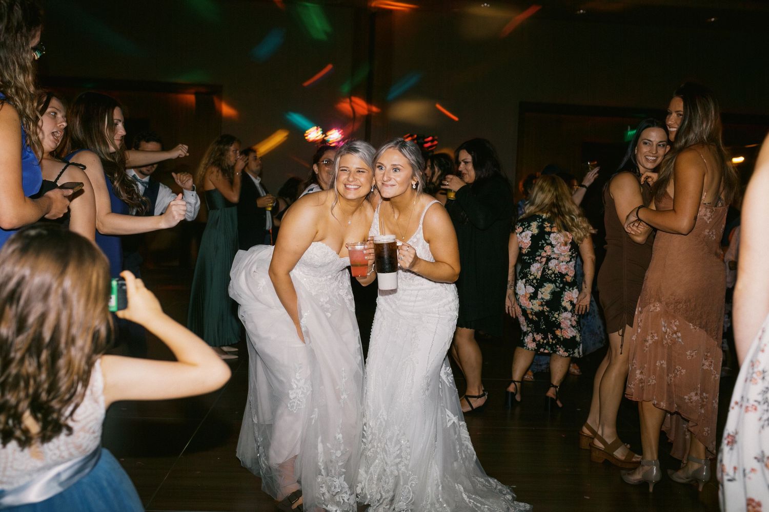 Wedding reception dance floor filled with guests celebrating under dimmed lighting at an evening party.