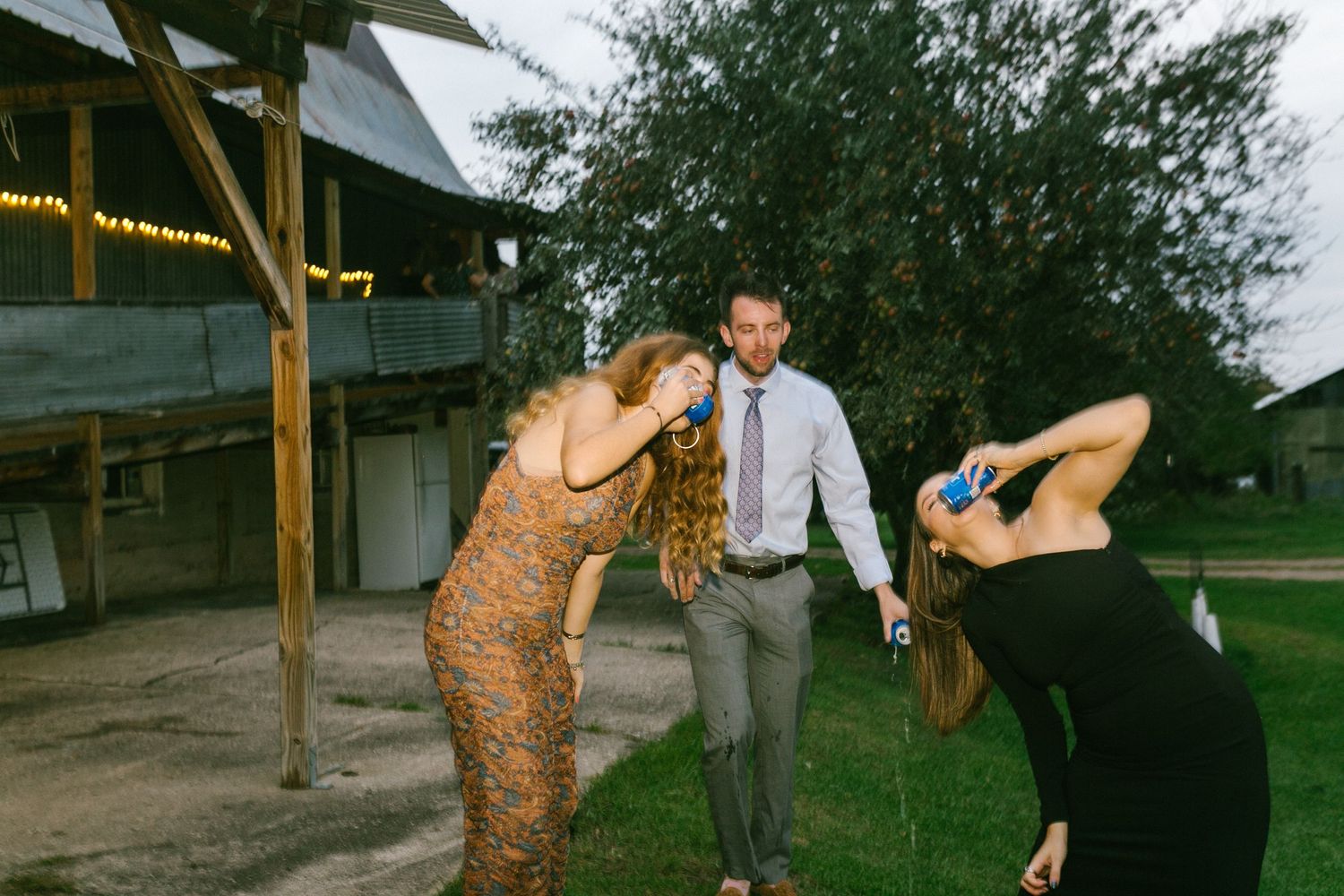 Wedding guests dancing playfully outdoors under a covered venue area during a celebration.