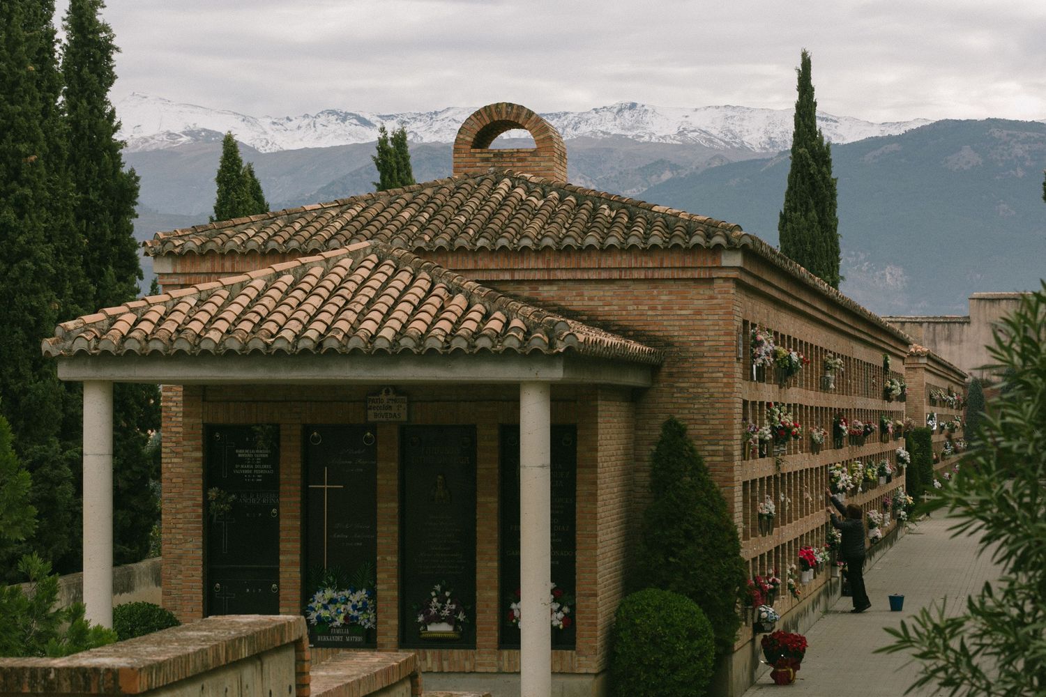 A columned pavilion with terracotta roof tiles overlooks snow-capped mountains in Granada.