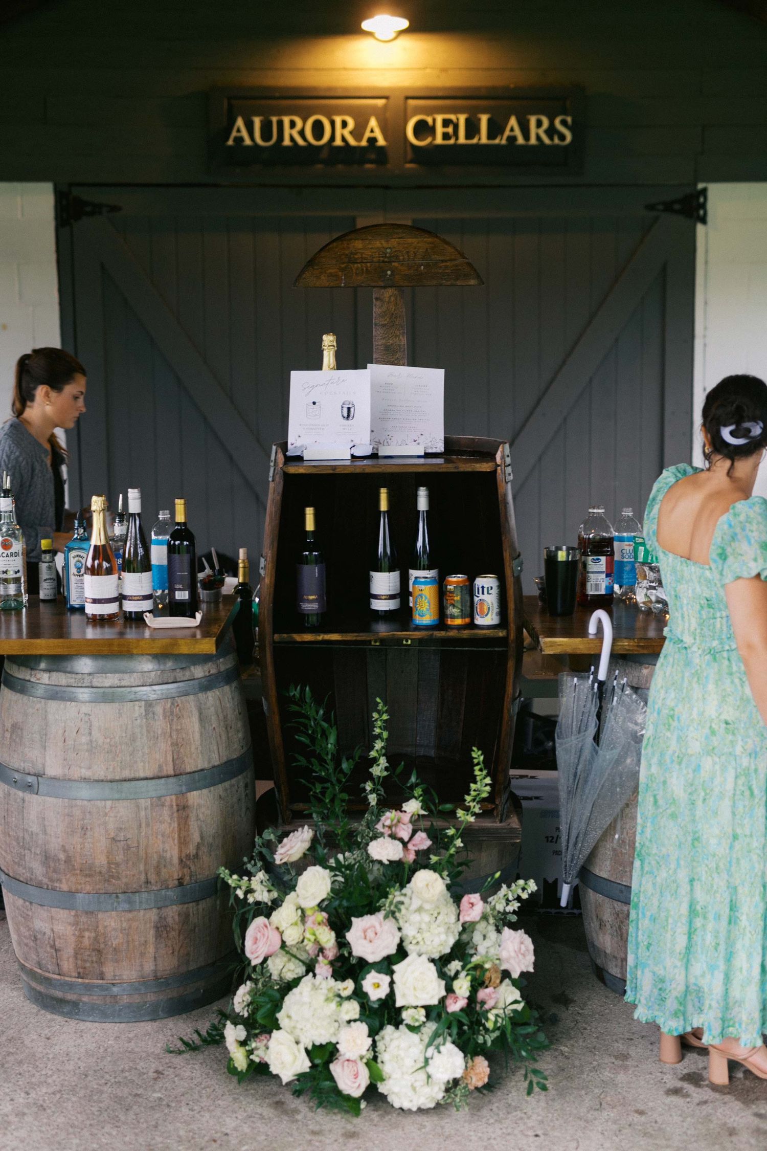 Wine tasting setup at Aurora Cellars with wooden barrels, floral arrangements, and mint green decor creating an elegant ambiance.