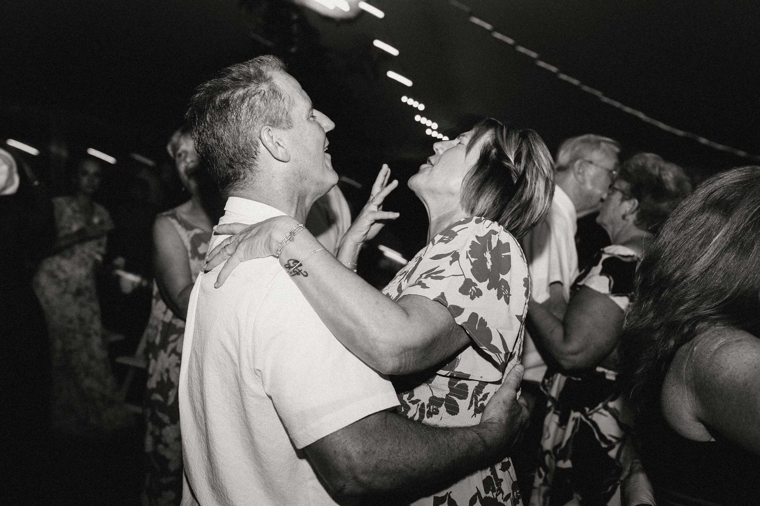 A couple earnestly sings at the top of their lungs while dancing at during a wedding reception.