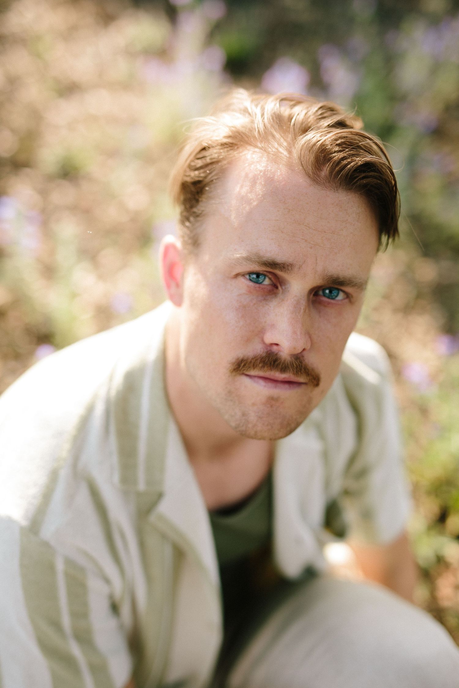 Portrait in a field with soft lighting and purple wildflowers in the background.