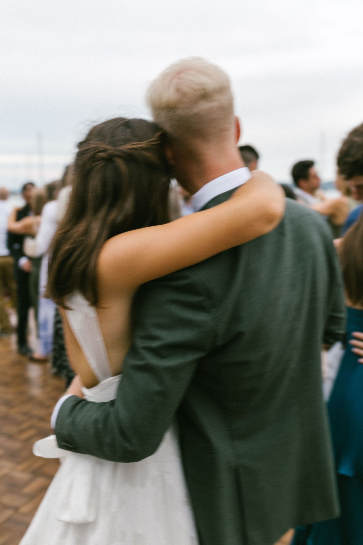 A couple dancing at an outdoor wedding reception with guests in the background.