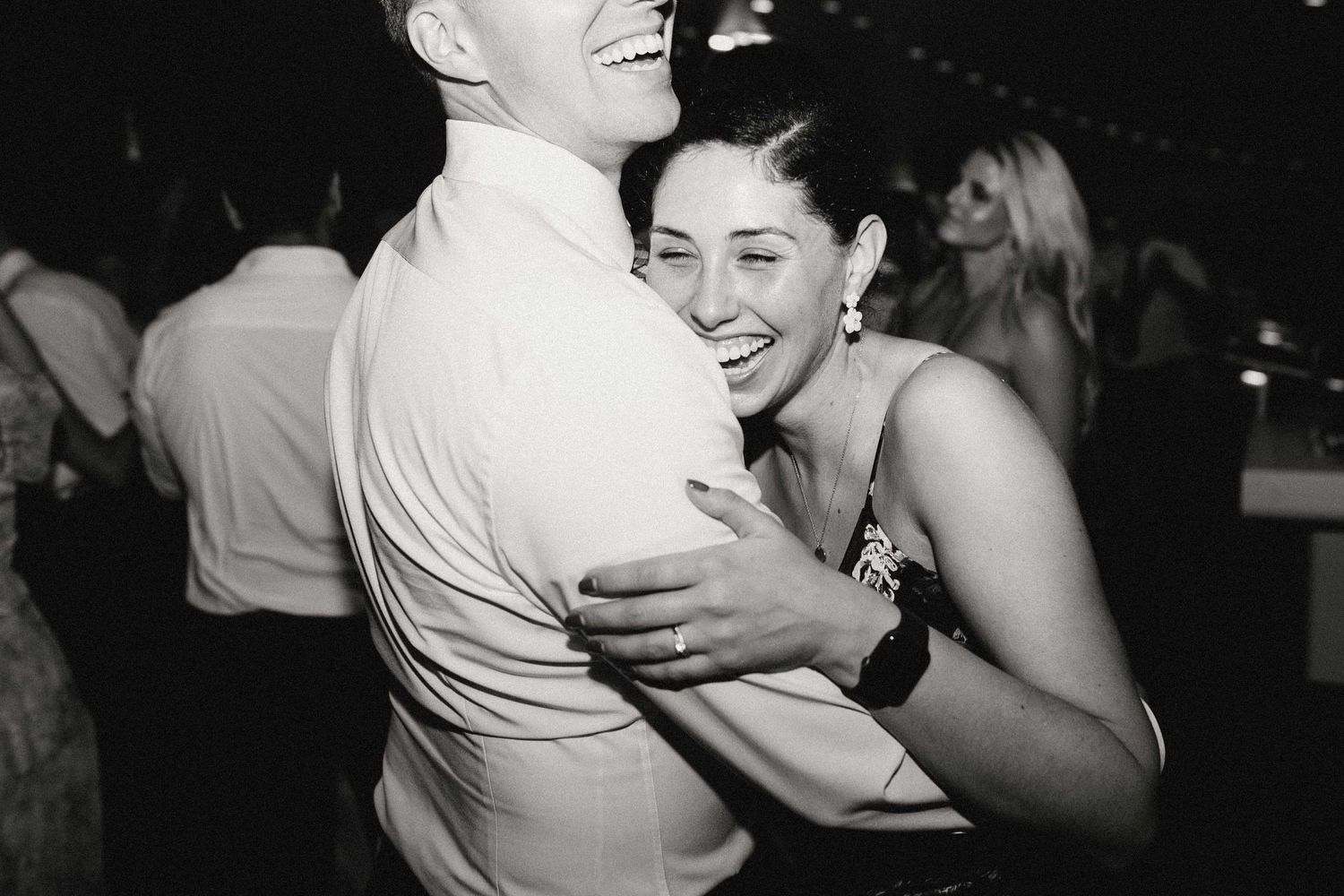 Black and white photo of people dancing together at a social gathering or party.