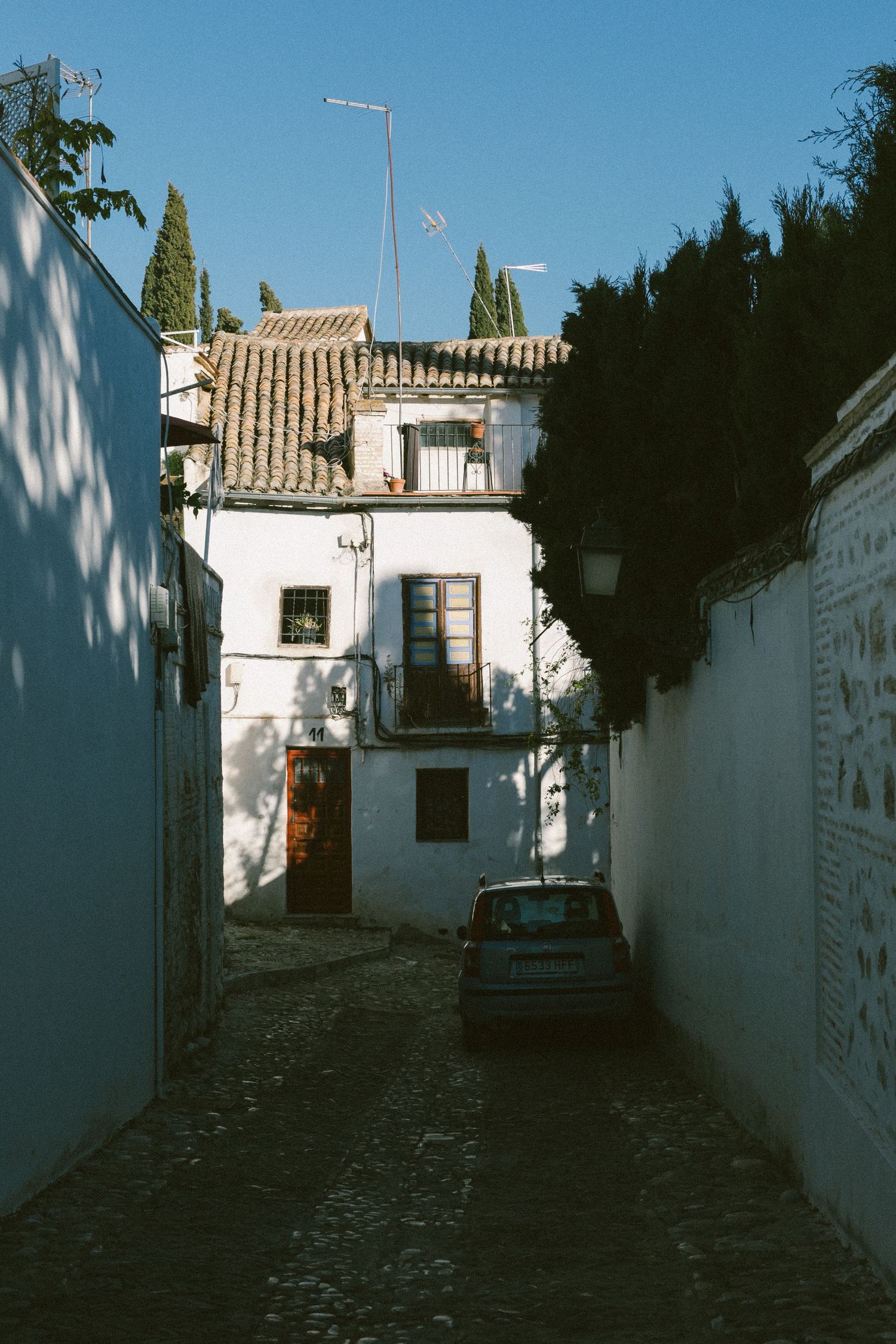 Narrow alley in Spanish neighborhood with white walls and traditional architecture.