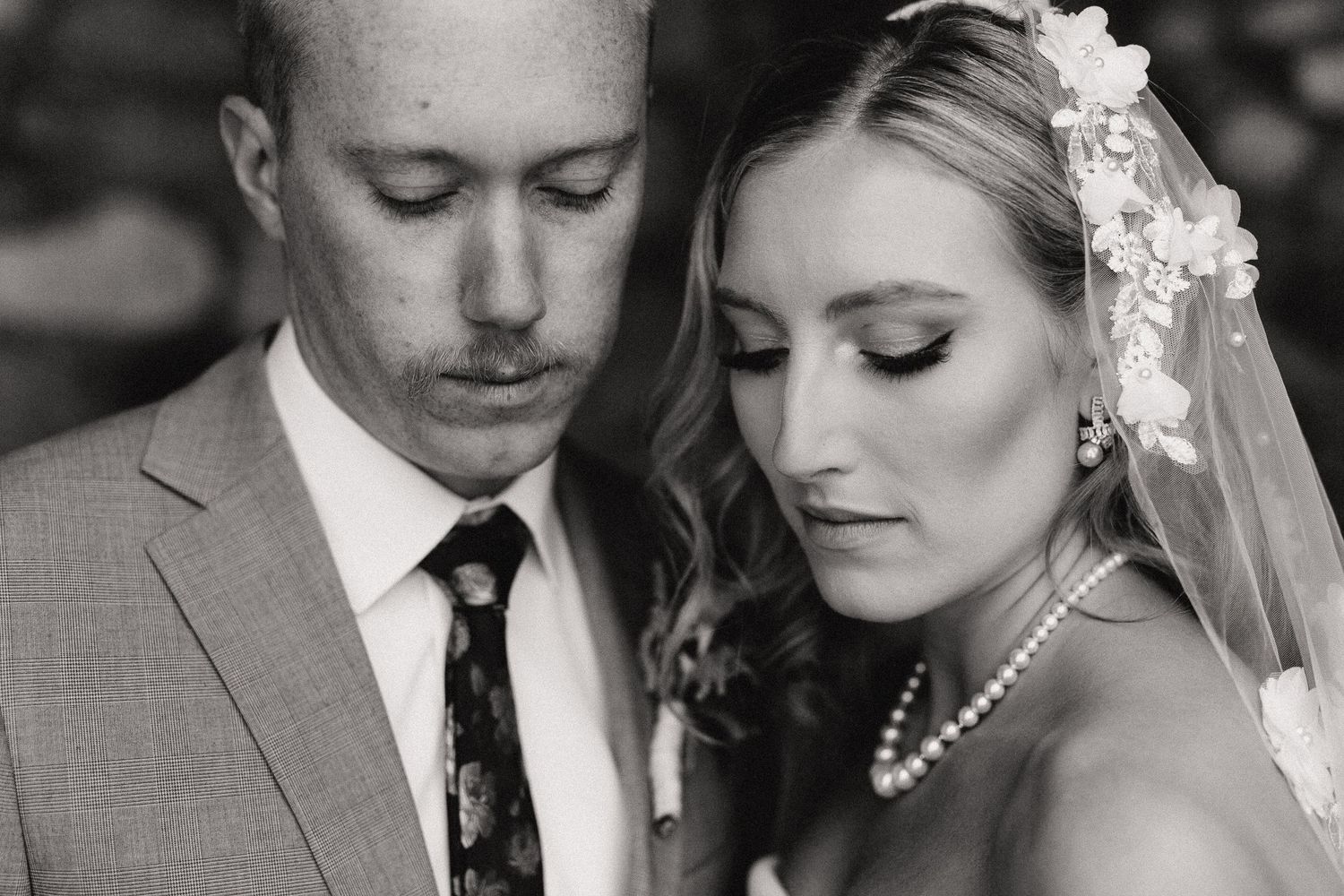 A series of intimate black and white wedding photos showing tender moments between a couple in formal attire.