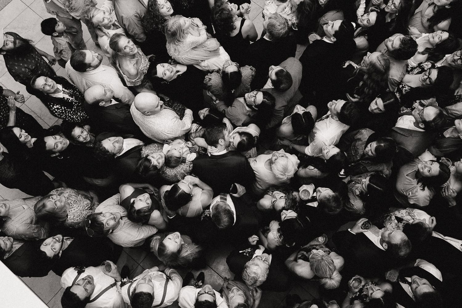 An overhead black and white shot of a crowded dance floor at a wedding reception.