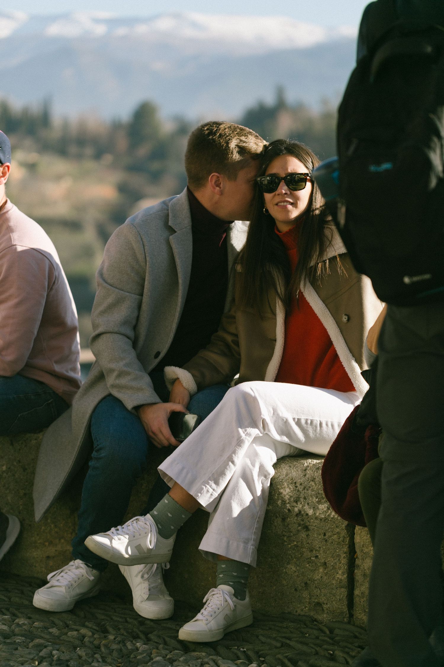 People enjoying a casual moment while sitting outdoors with mountain views in the background.