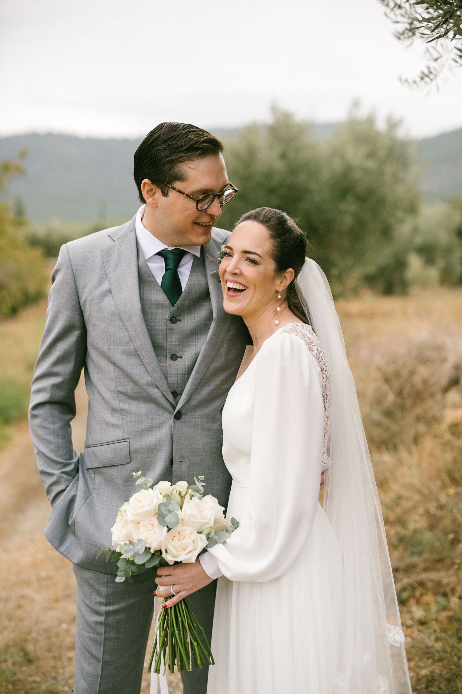 Bridal couple sharing a joyful moment together on their wedding day with mountains in the background.