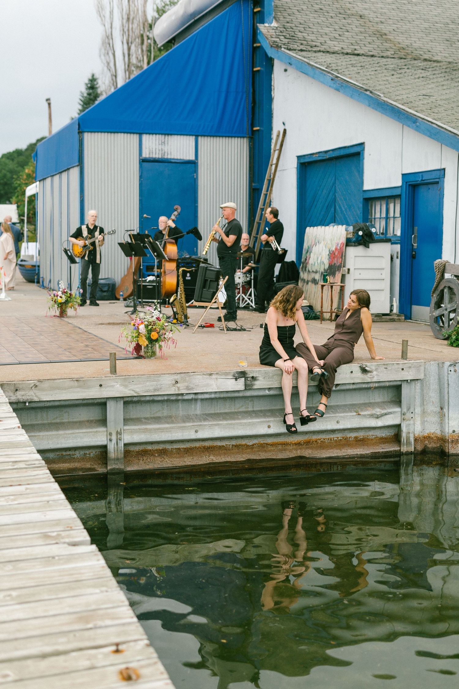 A sequence of photos showing someone falling into dark water from a wooden dock near blue buildings.