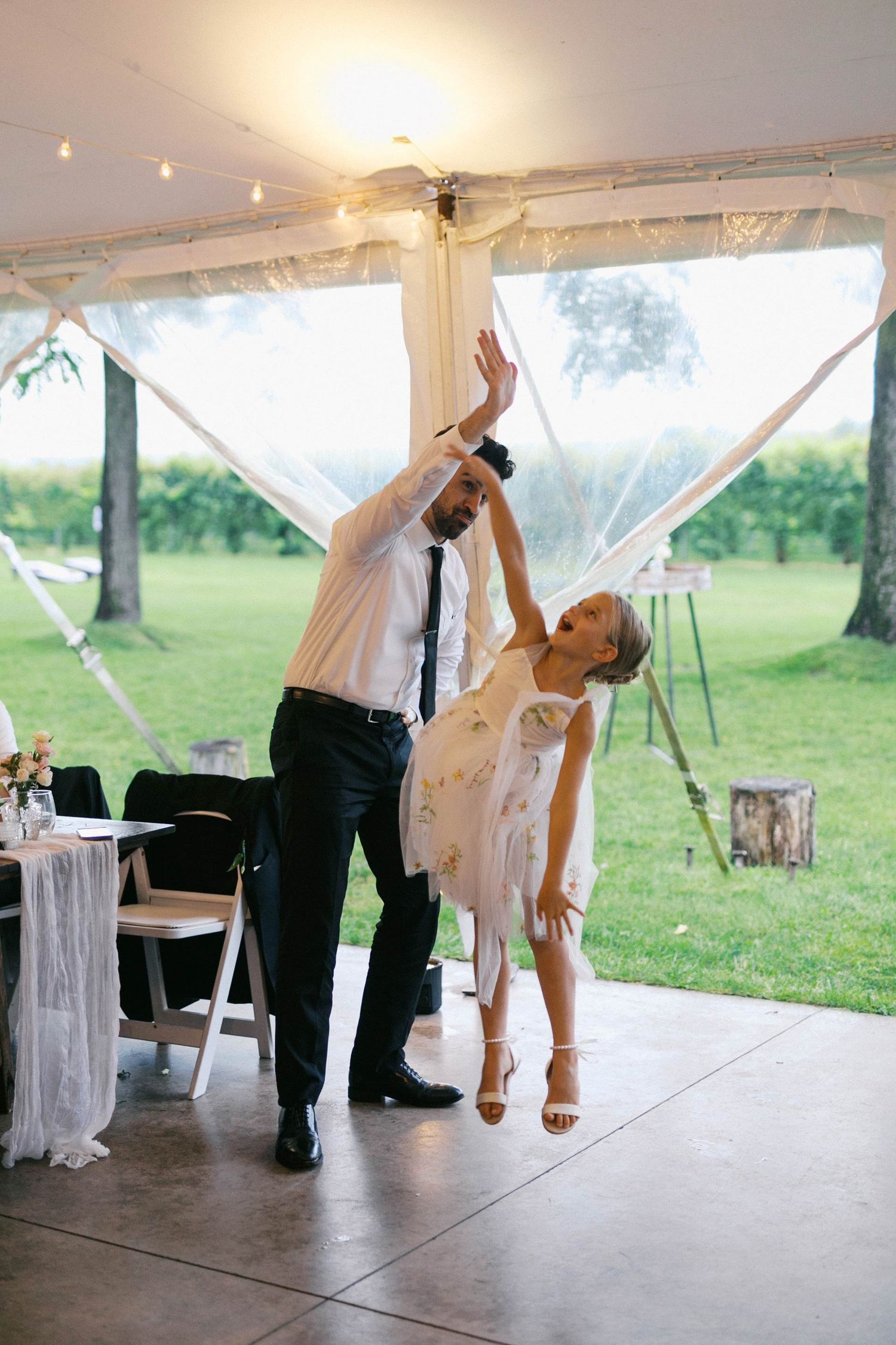 A young flower girl jumps to high five the wedding officiant.