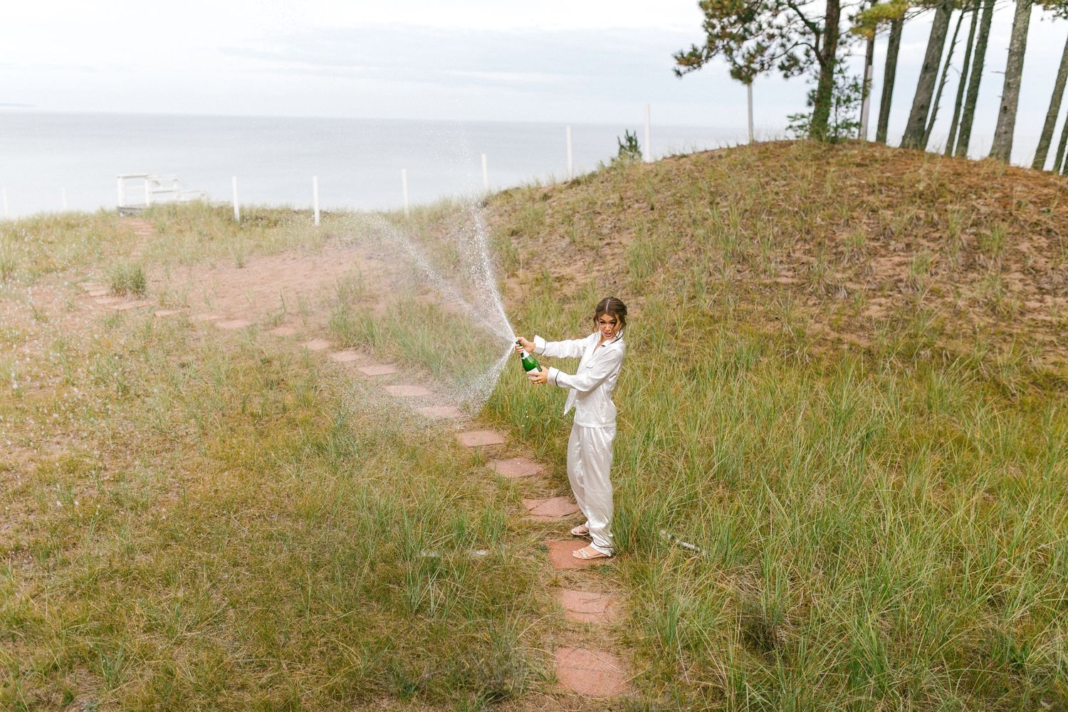 A young athlete in white athletic wear practices their form along a scenic coastal trail overlooking the ocean.