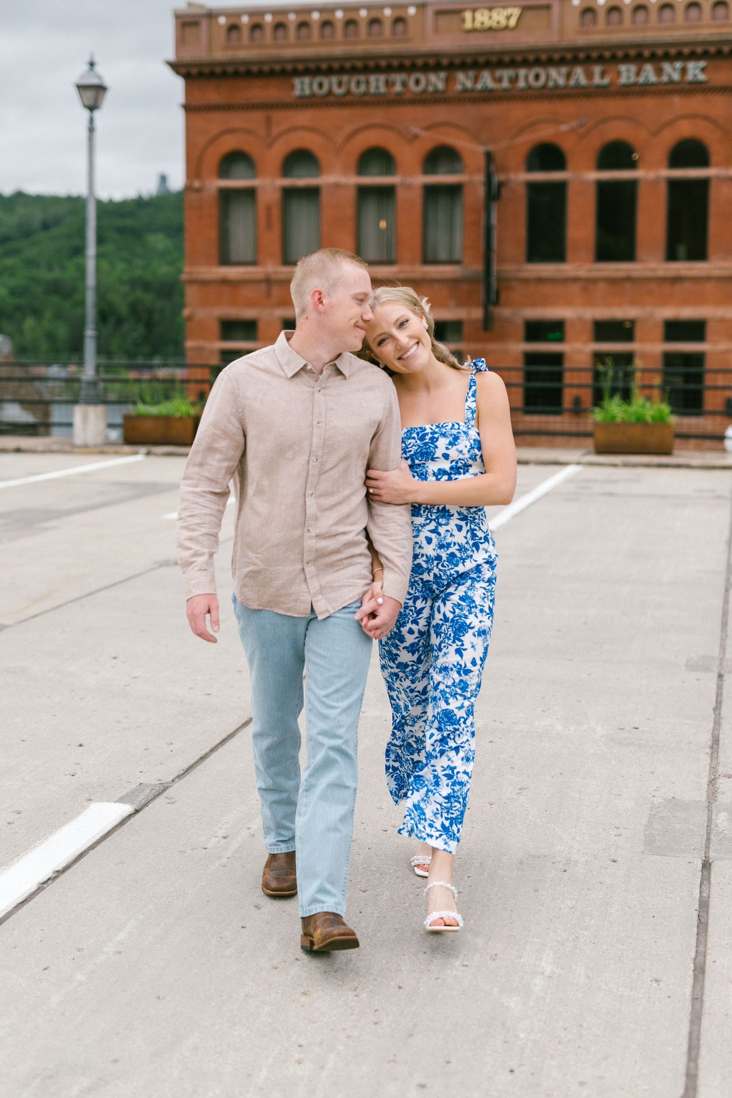 A couple taking a romantic stroll in front of the historic Houghton National Bank building.